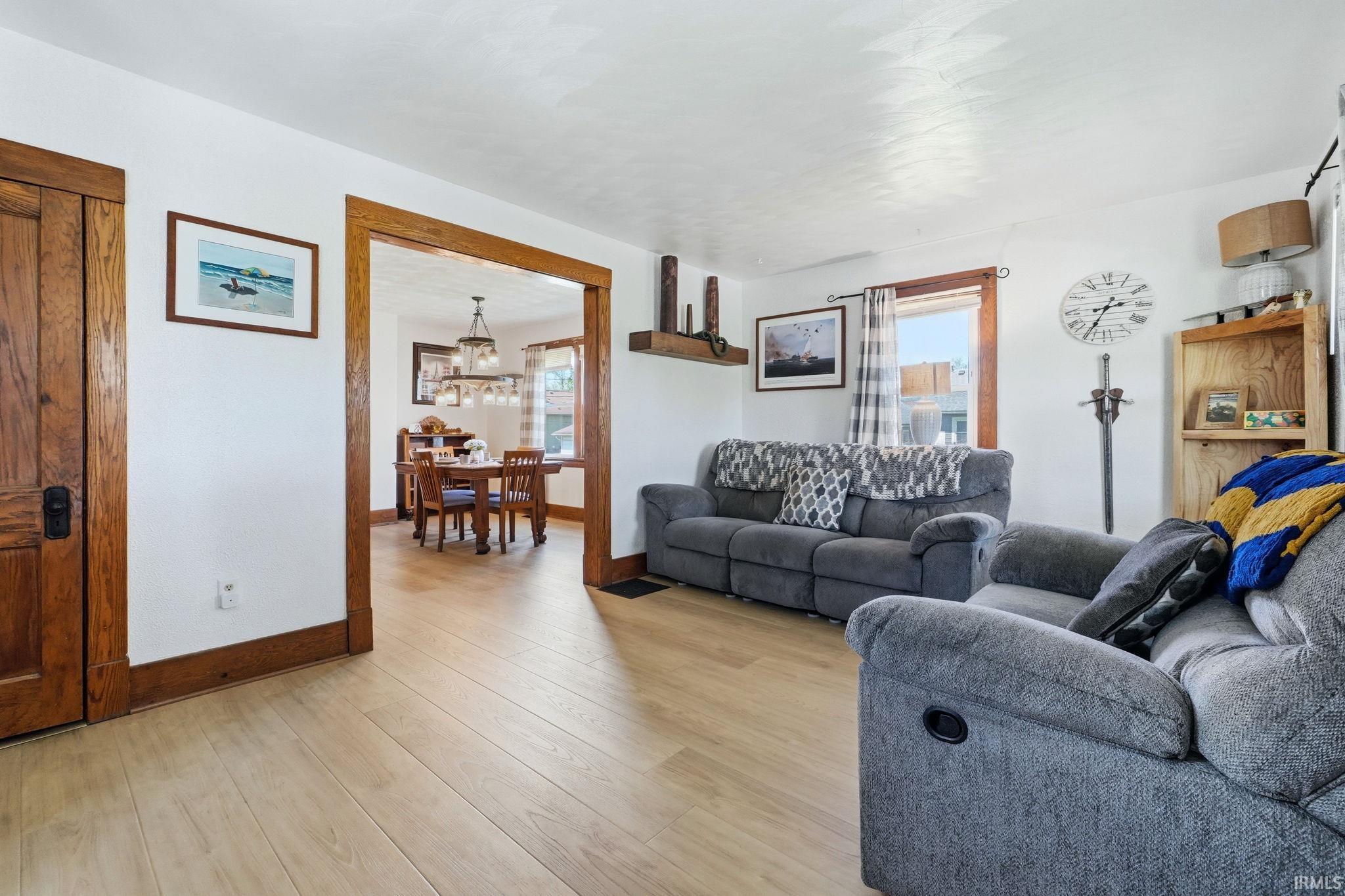 Light wood-finish flooring extends through the living area and into an adjacent room