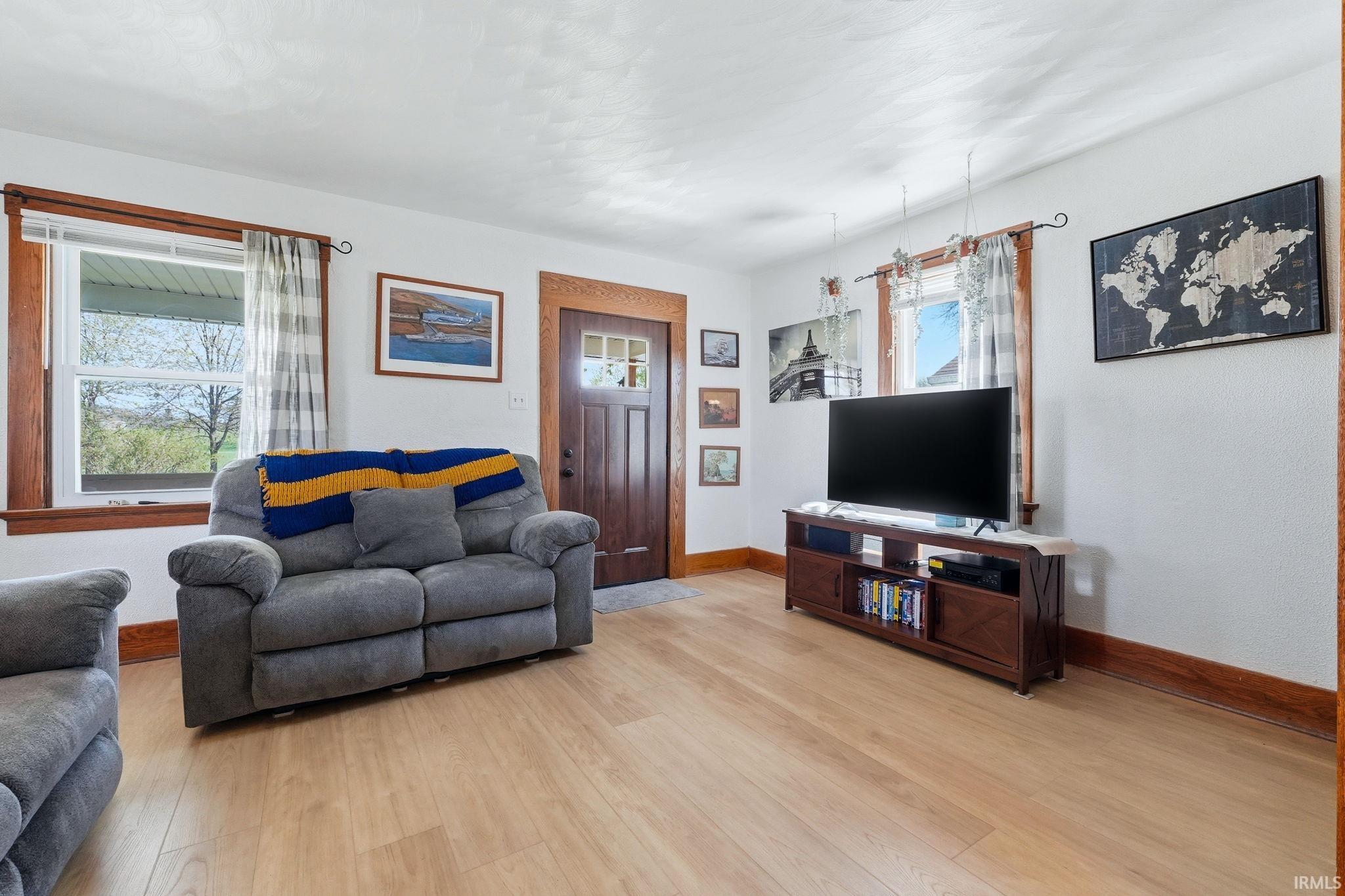 Living area featuring light wood-finish flooring, white walls, and dark wood trim