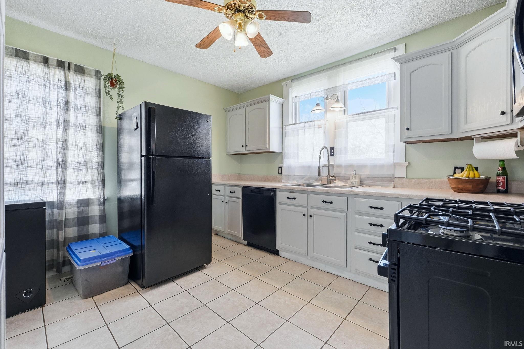 Kitchen featuring light-toned cabinetry, a ceiling fan, tiled flooring, and a double-basin sink with a gooseneck faucet