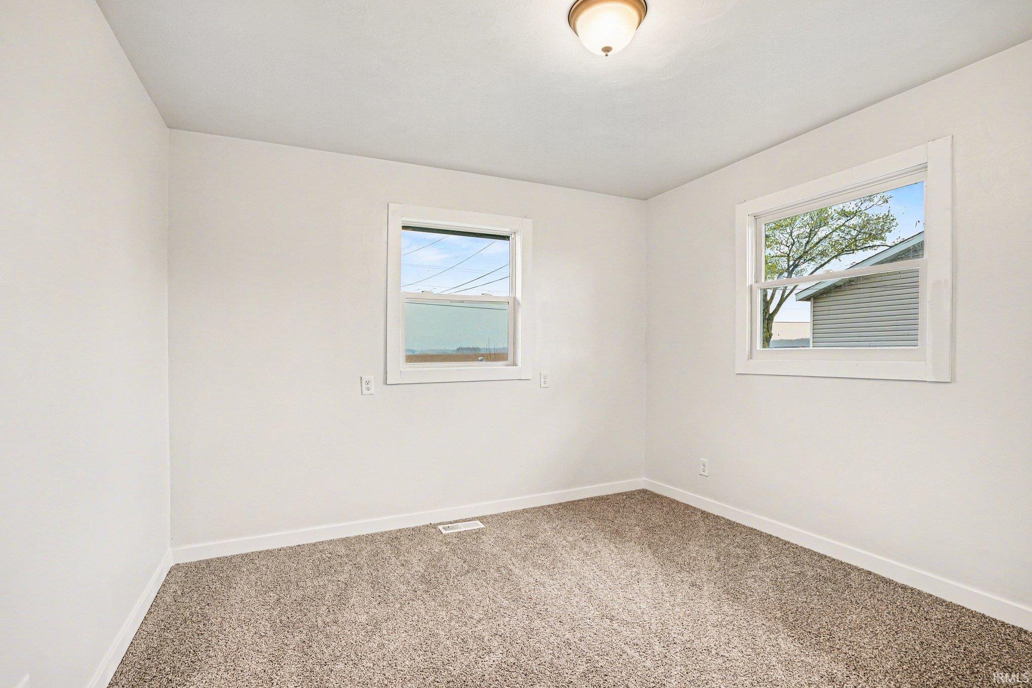 Spare room featuring baseboards and light colored carpet