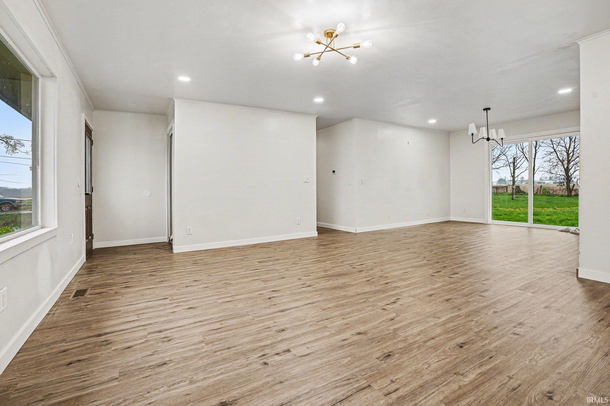 Unfurnished room featuring hanging lights and light wood-type flooring