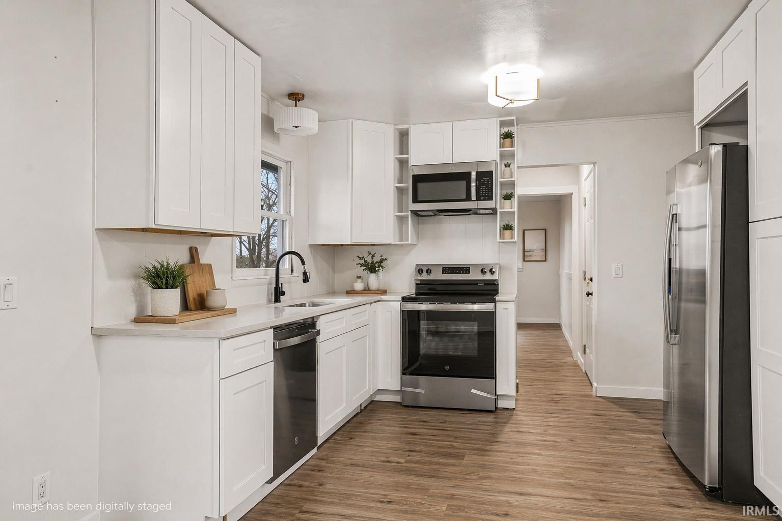 Kitchen with open shelves, stainless steel appliances, white cabinetry, and ornamental molding.Virtually staged