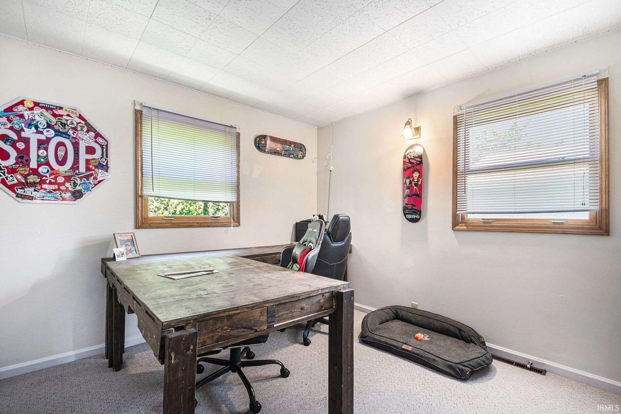 Room featuring two windows with wood trim, wall-mounted sconce lighting, and a textured ceiling
