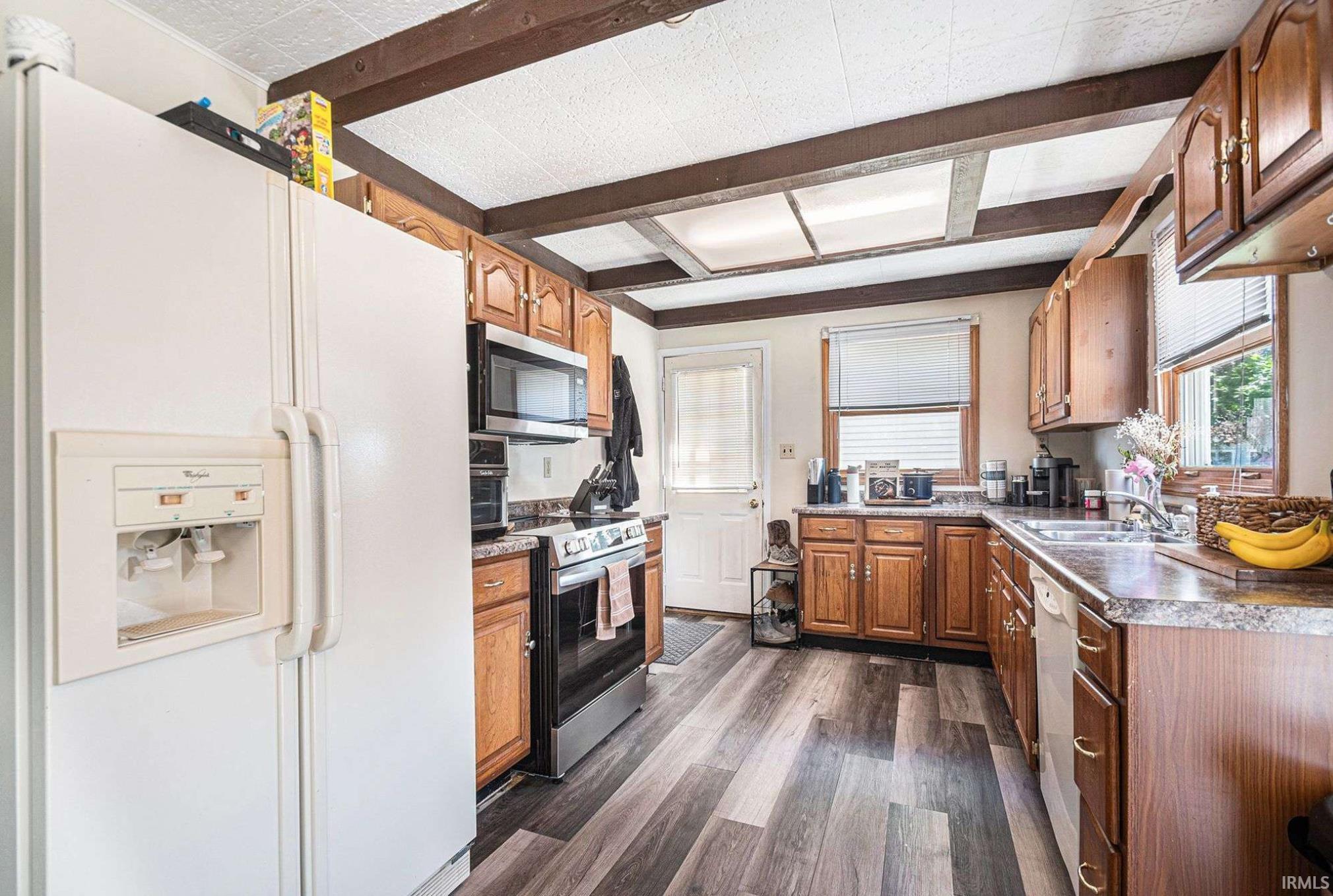 Kitchen featuring wood-finish flooring, exposed ceiling beams, light wood cabinetry, and laminate countertops