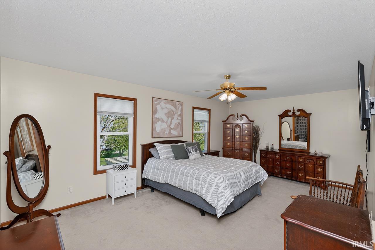 Carpeted bedroom with ceiling fan and baseboards