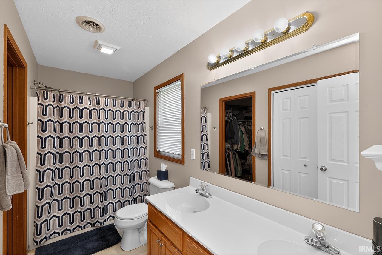 Bathroom featuring double vanity, a shower with shower curtain, and a spacious closet
