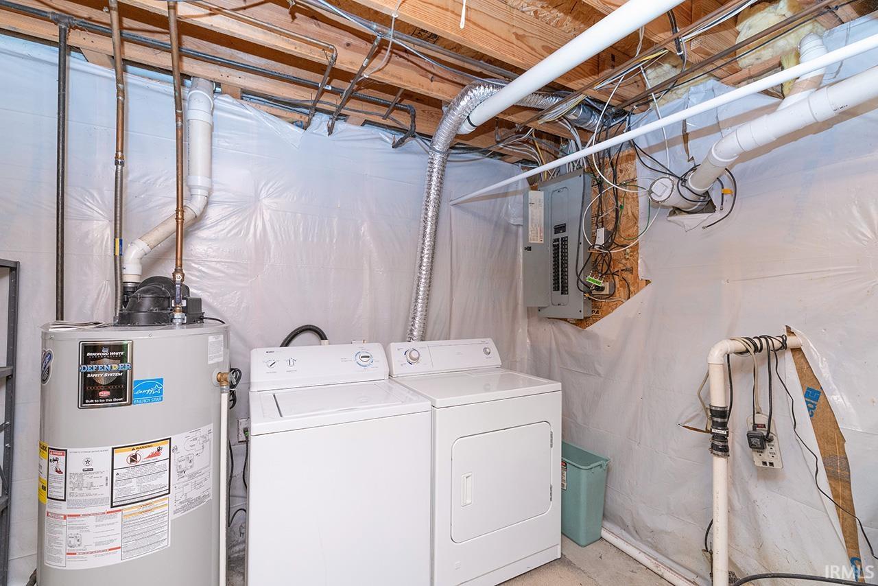 Laundry area featuring gas water heater, electric panel, separate washer and dryer, and unfinished concrete floors