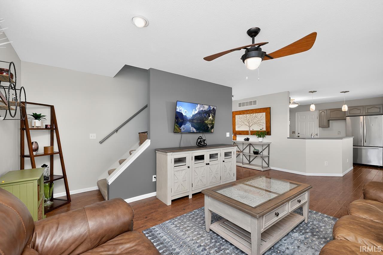 Living room with ceiling fan and dark wood-style flooring