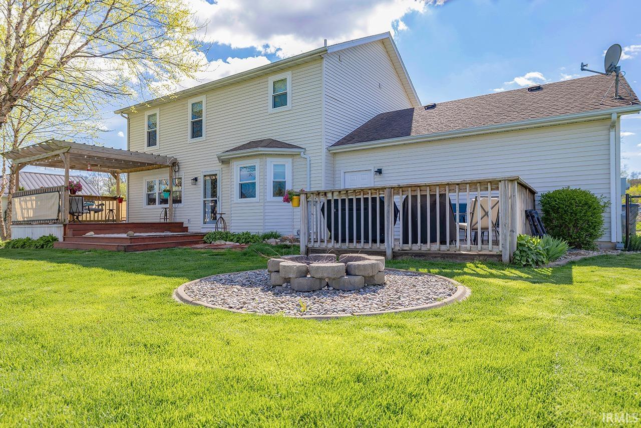 Rear view of property with a deck, a yard, and a fire pit