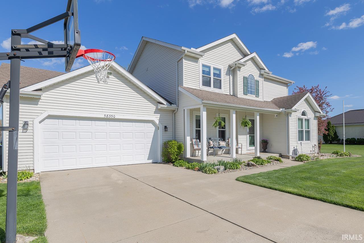 Traditional home featuring a front lawn, a porch, an attached garage, and concrete driveway