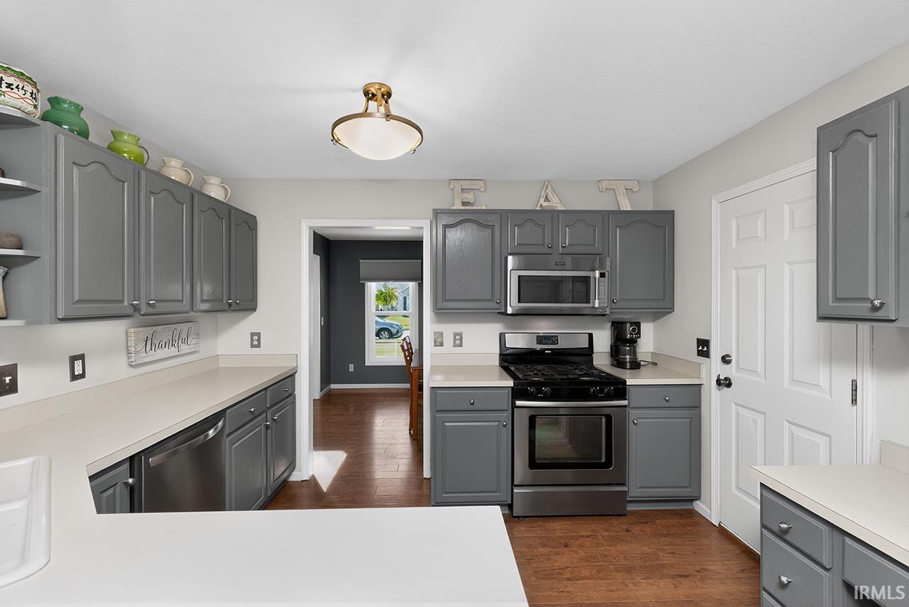 Kitchen featuring gray cabinets, stainless steel appliances, light countertops, and open shelves