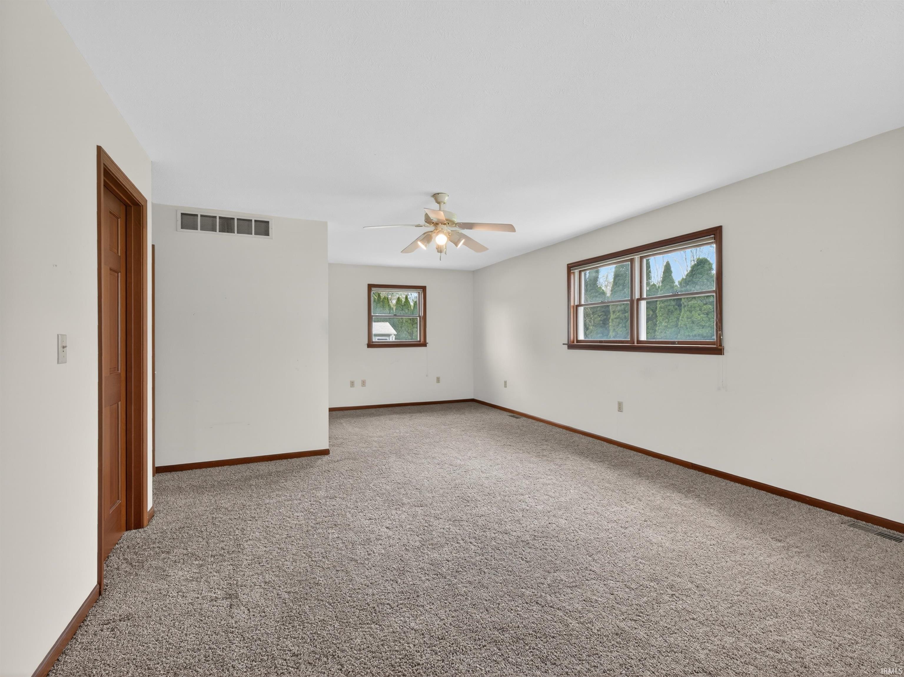 Spacious room featuring neutral carpeting, white walls, and wood trim