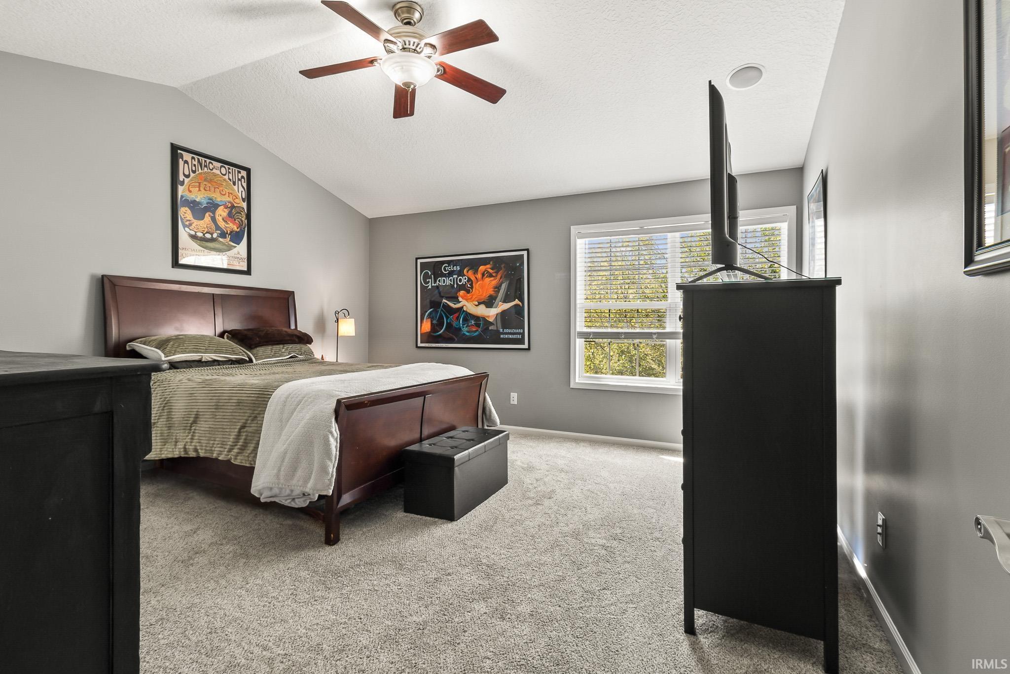 Carpeted room featuring a vaulted ceiling with a fan light fixture, light gray walls, and a window with blinds