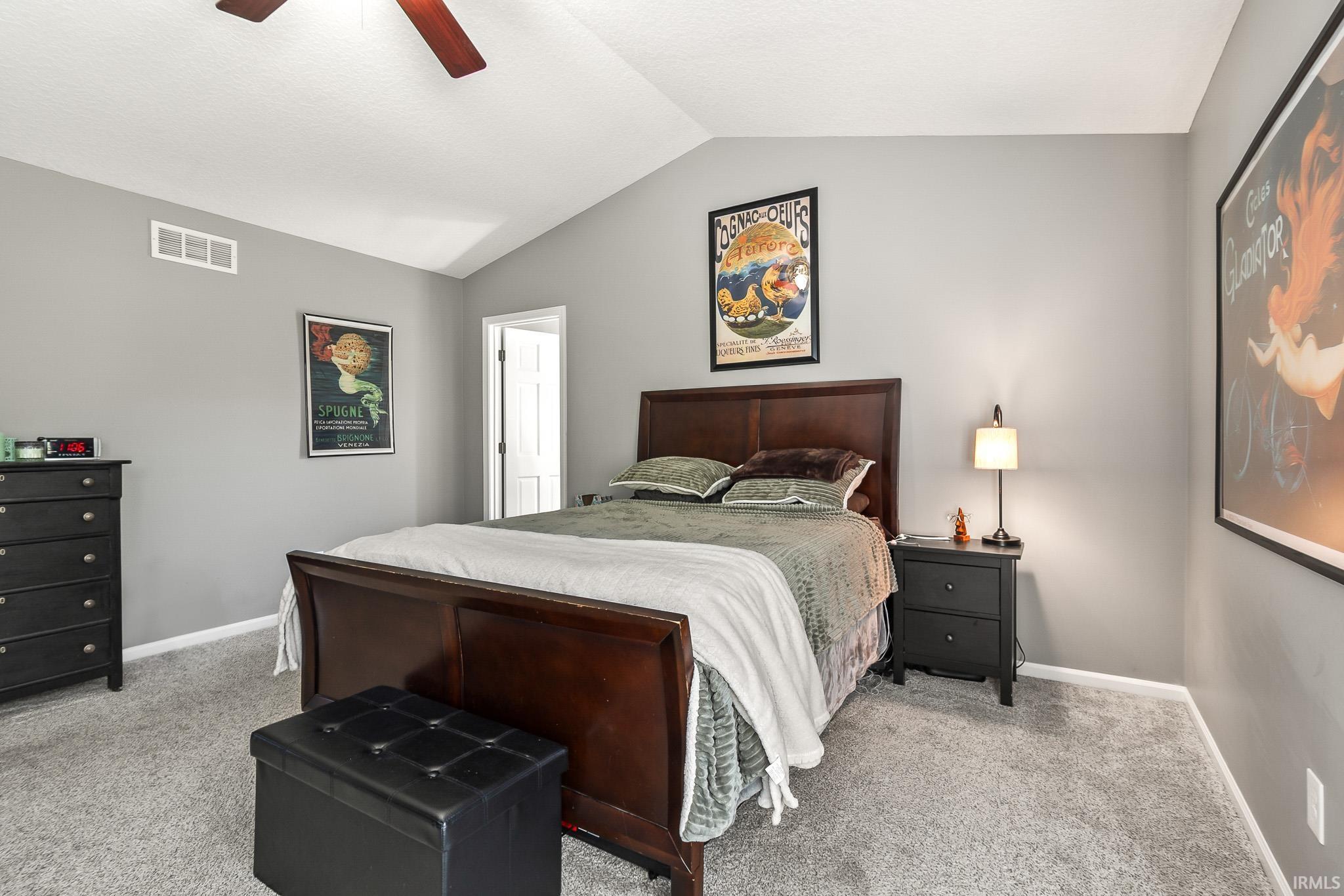 Spacious room featuring vaulted ceilings, light gray wall paint, and gray carpeting