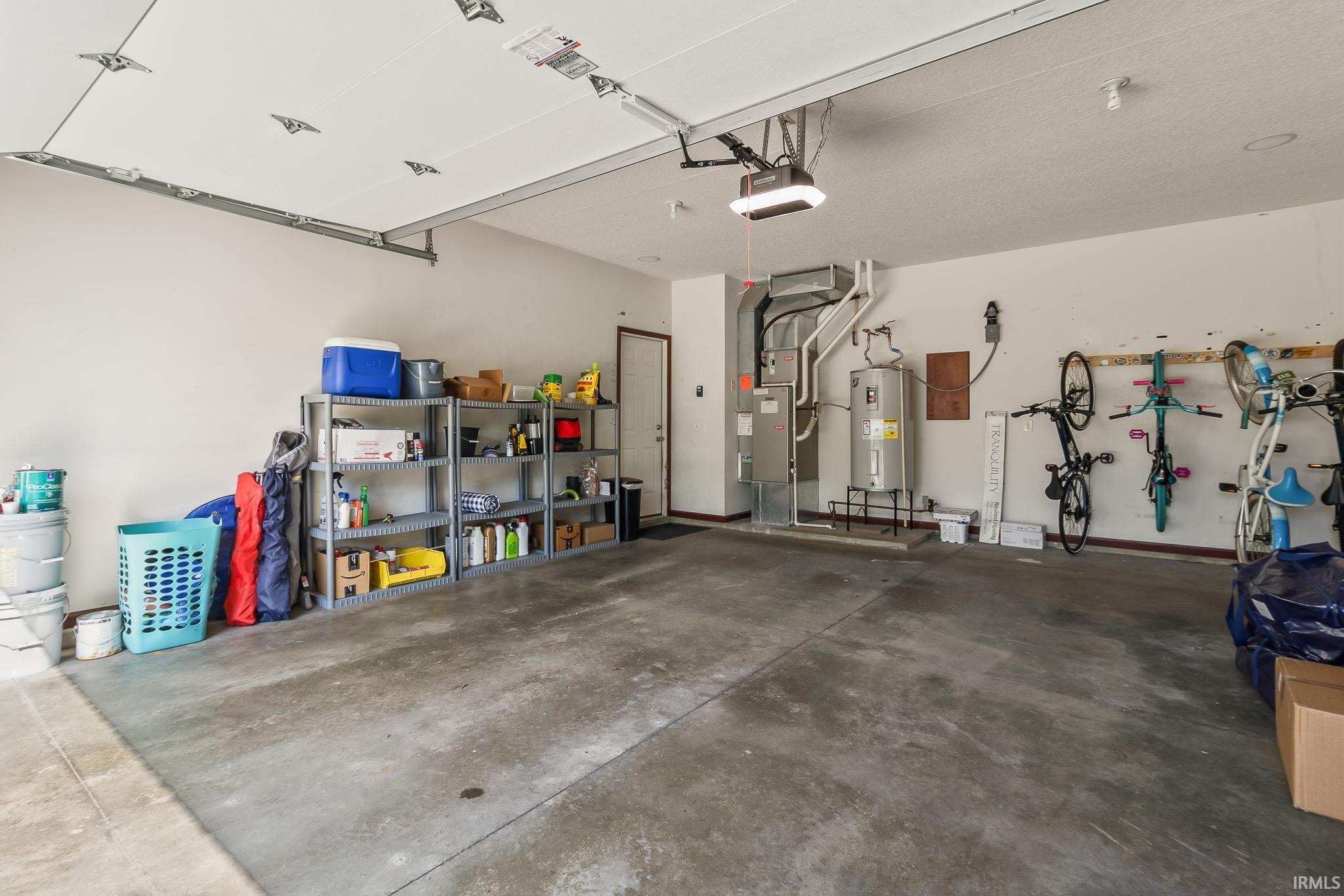Spacious garage featuring a concrete floor, white walls, overhead lighting, and an automatic garage door opener