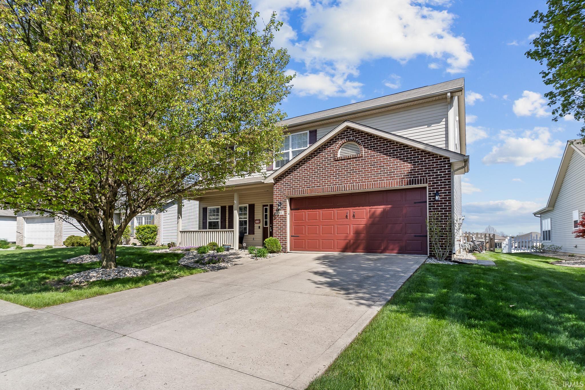 Two-story residence featuring brick and siding exterior, an attached garage with a red door, and a concrete driveway