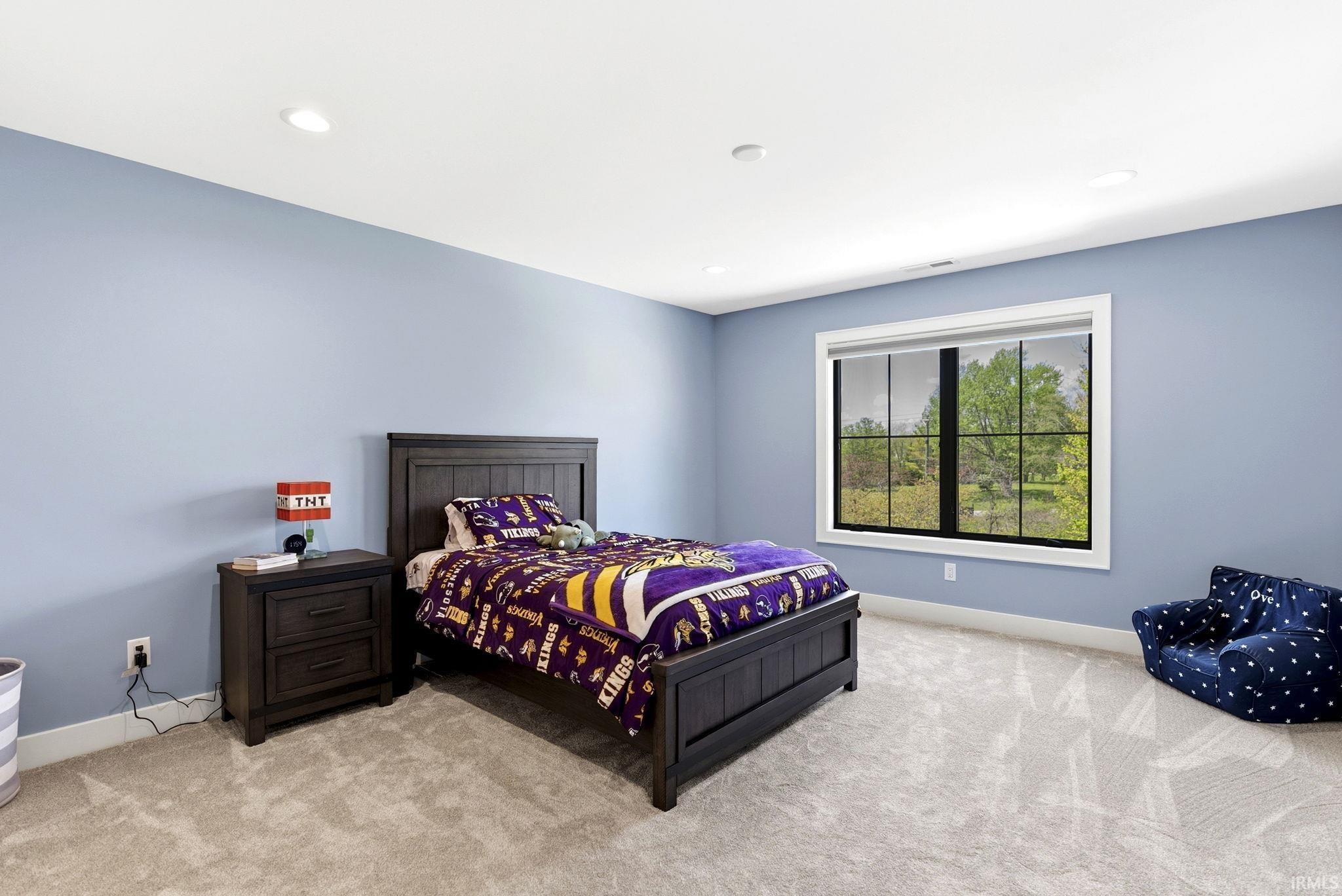 Spacious room featuring light blue walls, recessed ceiling lighting, and light-toned carpeting