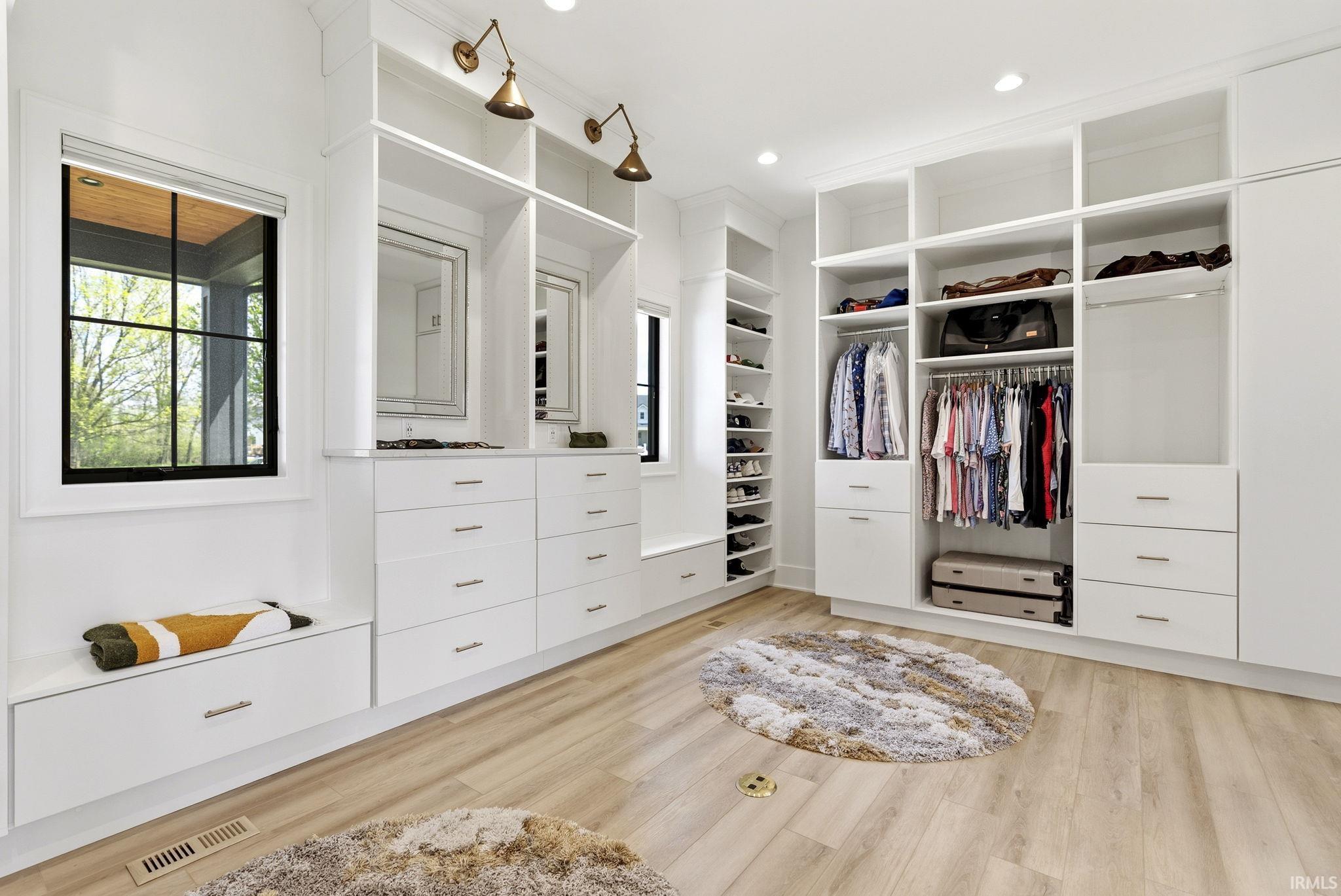 Spacious walk-in closet featuring extensive built-in white cabinetry, integrated shelving, hanging rods, and ample drawer storage