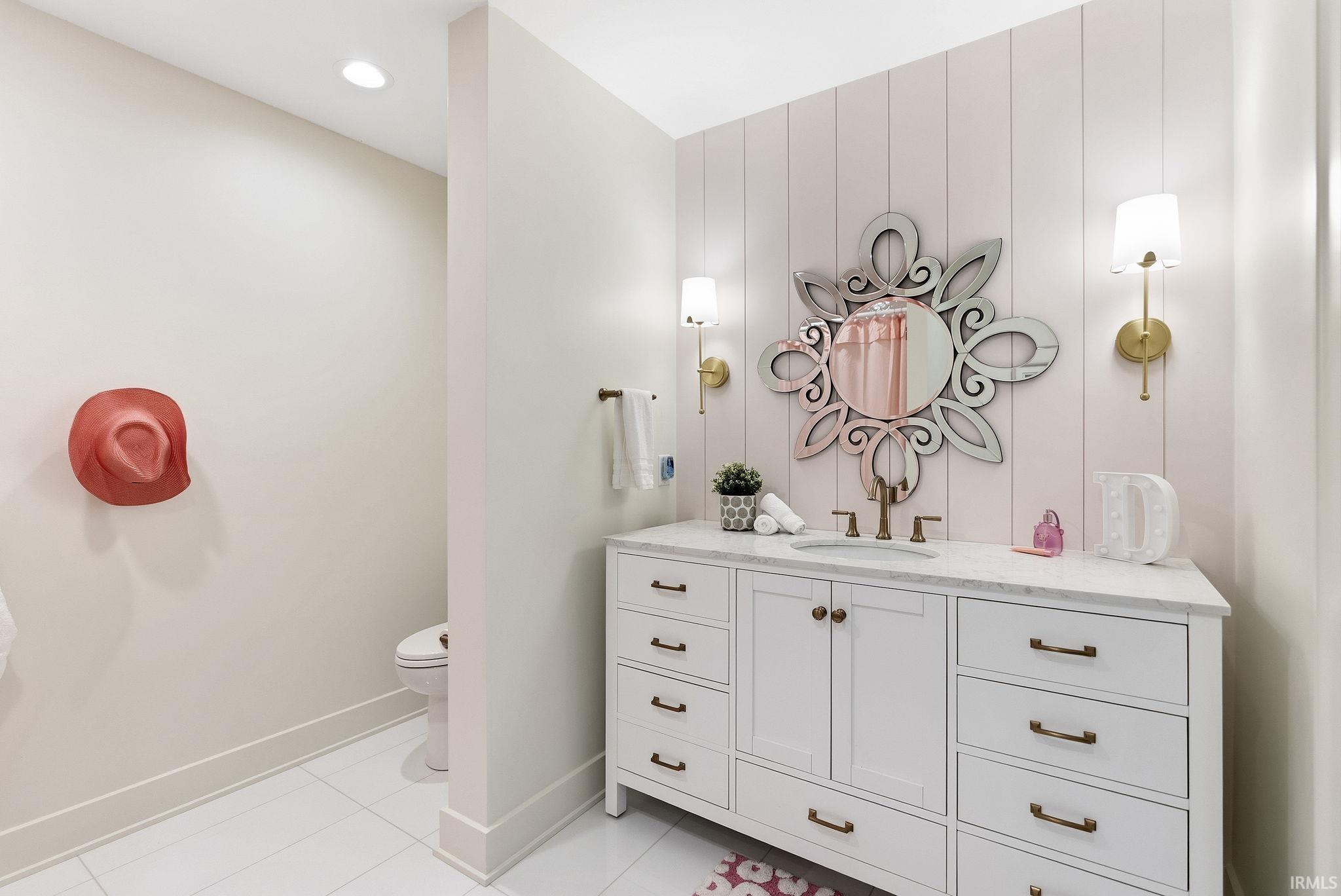 Single vanity with white cabinetry, bronze hardware, and a light-toned countertop