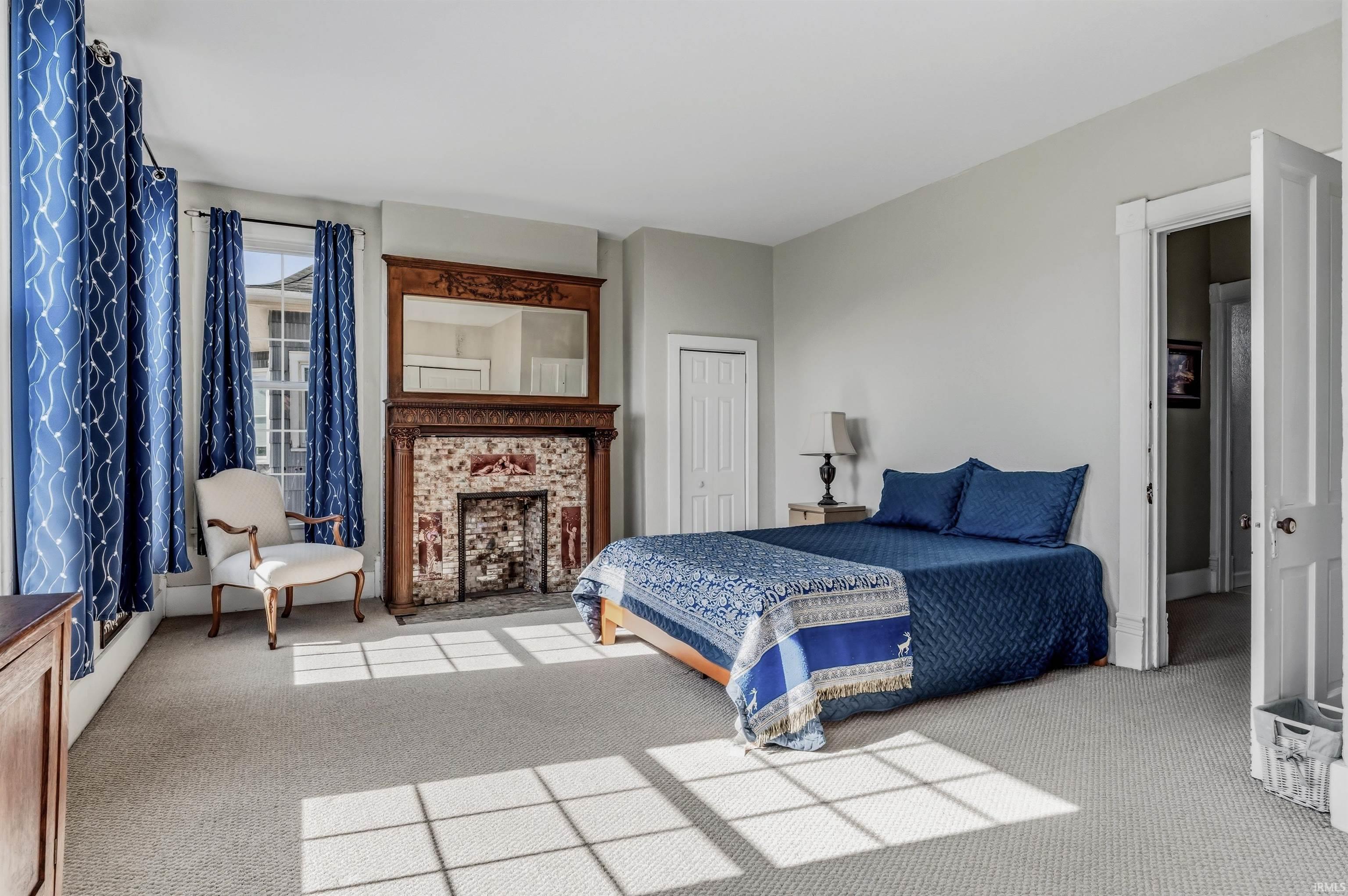 Bedroom with light colored carpet, a closet, and a fireplace
