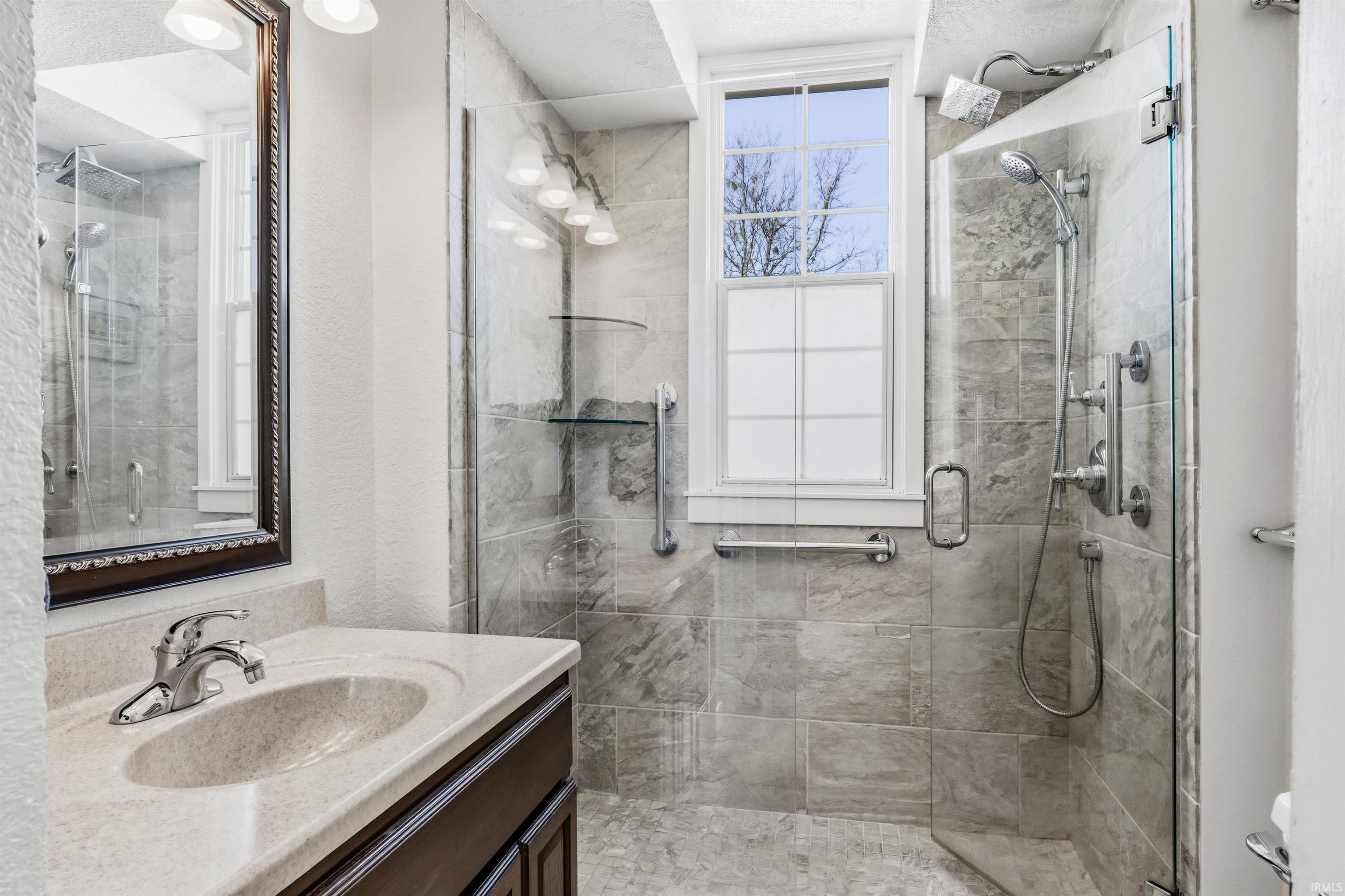 Bathroom with vanity, a stall shower, and a textured wall