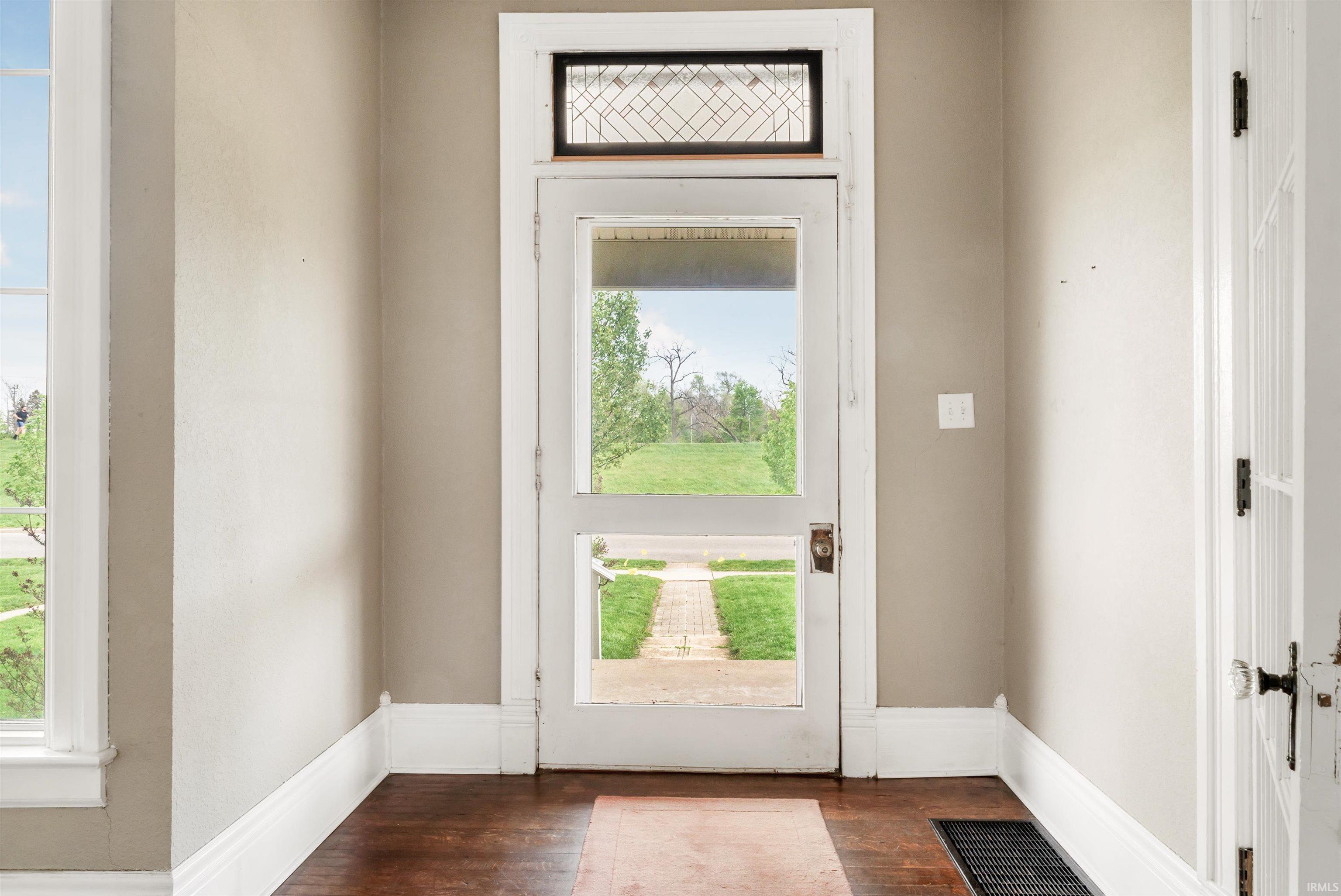 Entryway featuring a full-light door with leaded glass transom, wood-finish flooring, and white trim