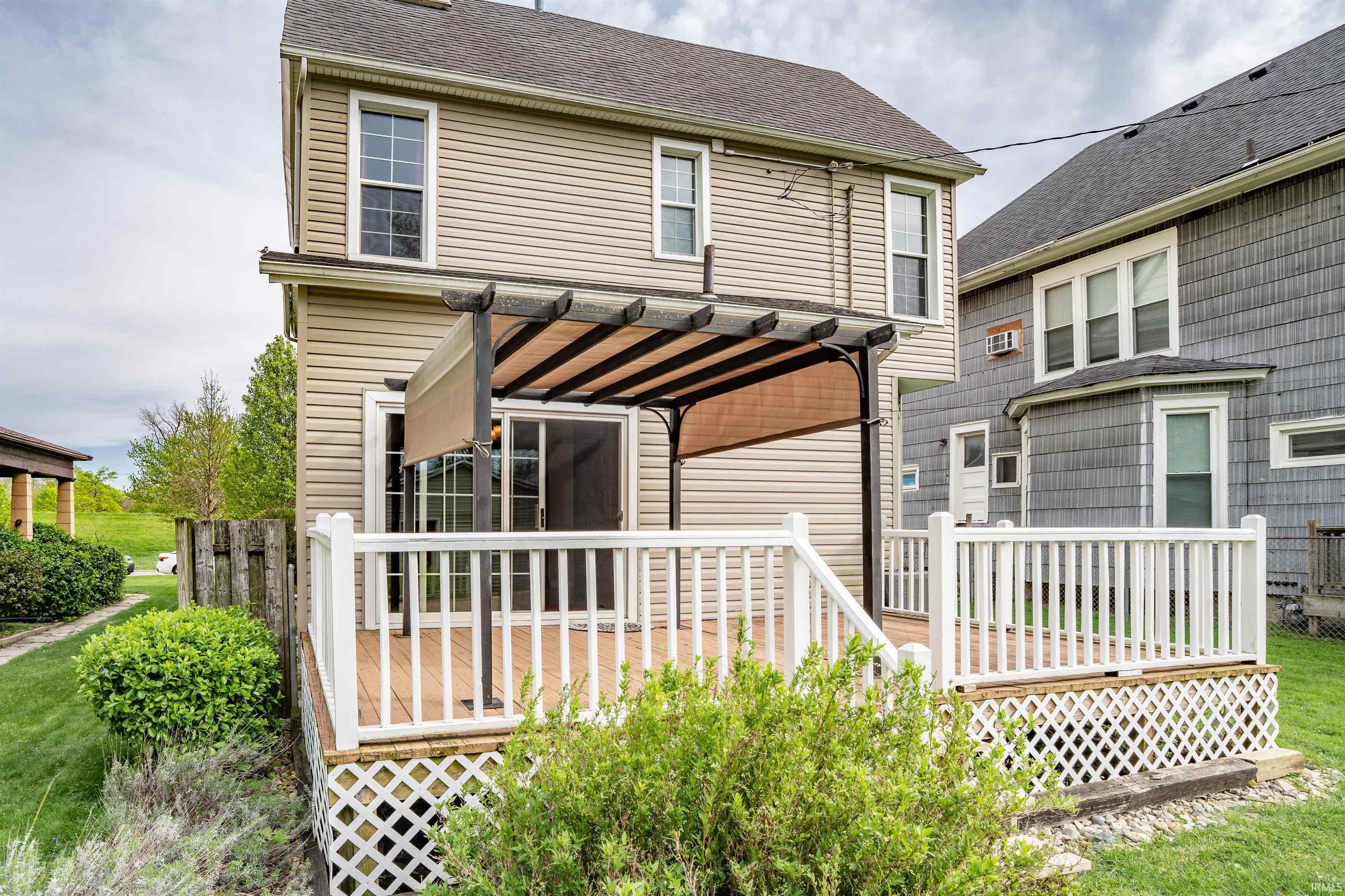 Rear exterior with a multi-level wood-finish deck featuring white railings and lattice skirting