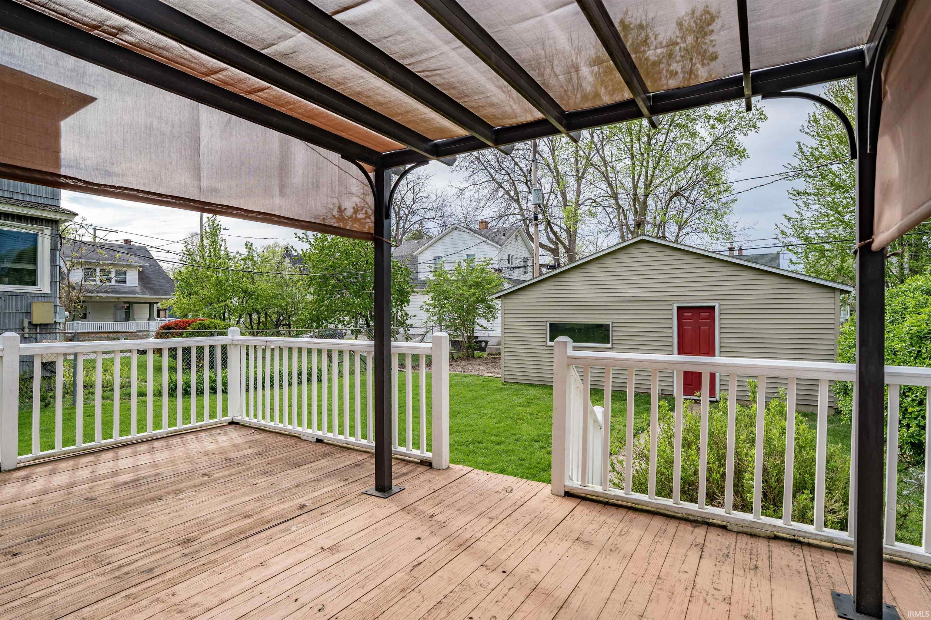 Expansive wood-finish deck featuring white railings and a covered pergola