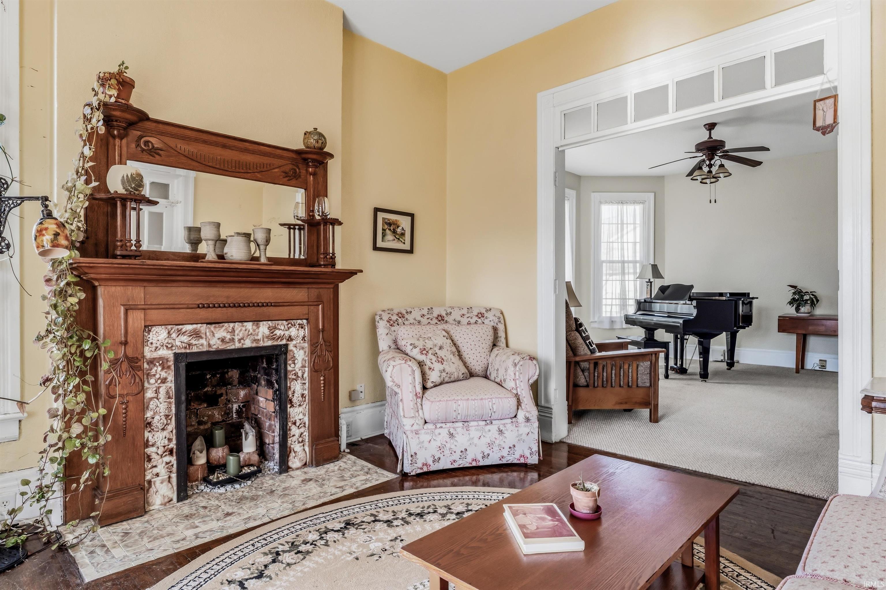 Living room with wood finished floors, a ceiling fan, and a premium fireplace
