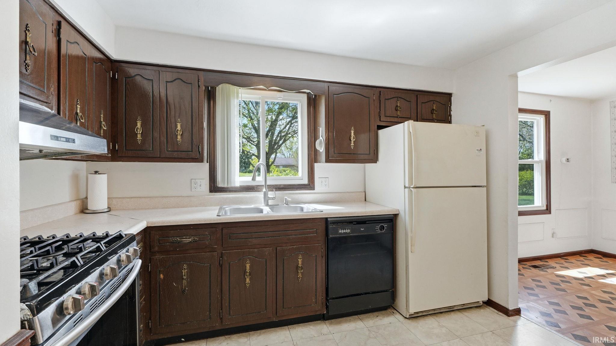 Kitchen featuring brown cabinetry, light-toned countertops, and a double basin sink