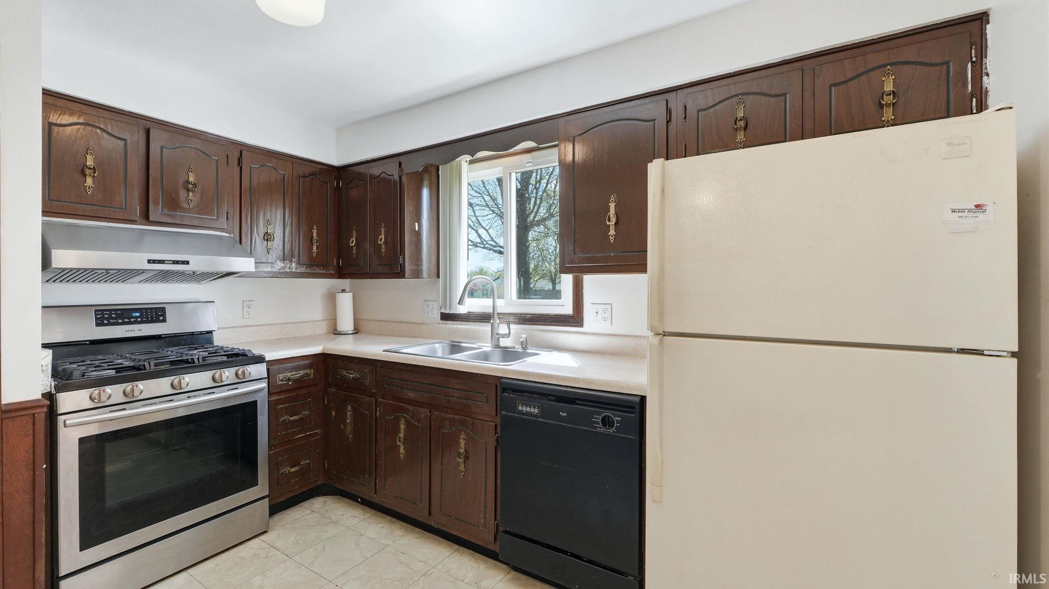 Kitchen featuring dark wood cabinetry, light countertops, and a stainless steel gas range with coordinating hood
