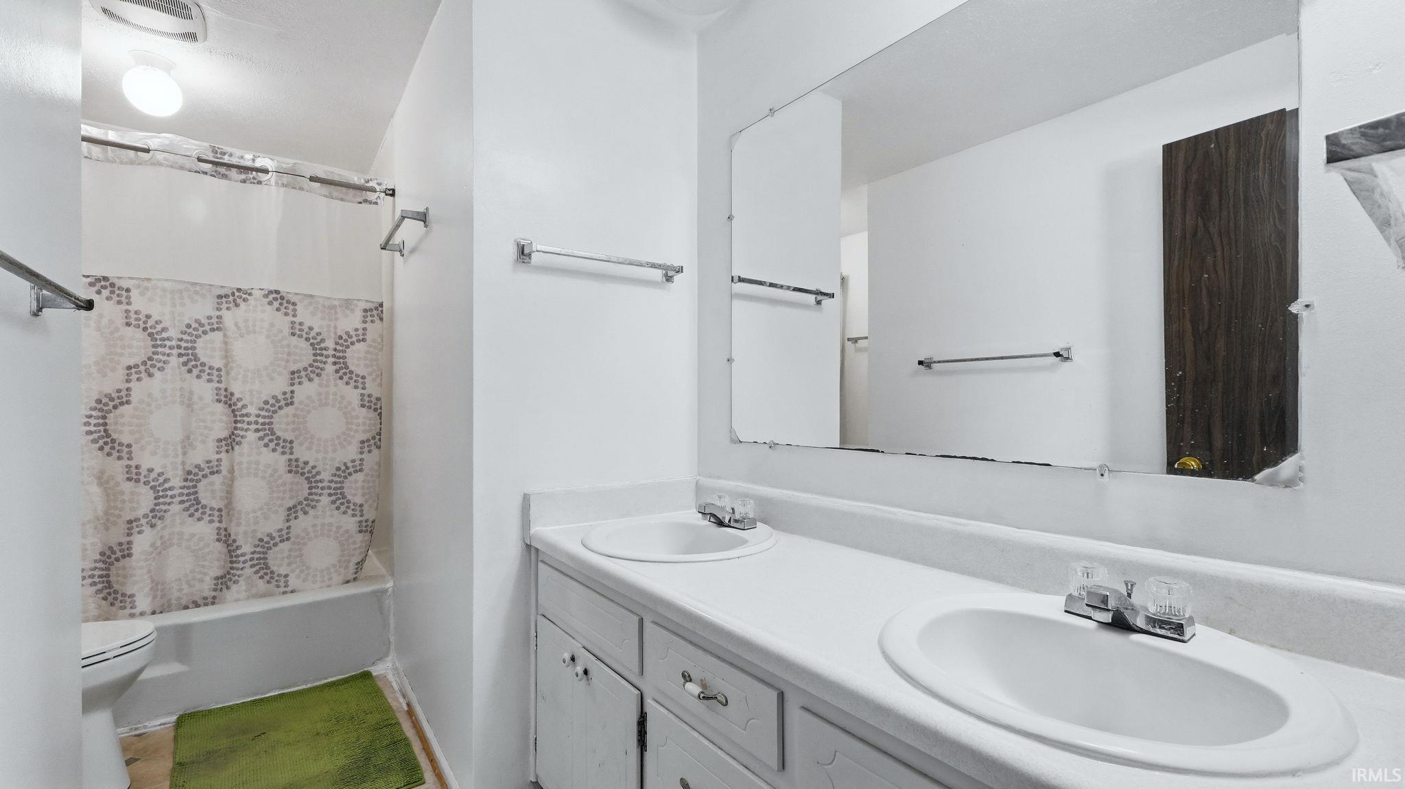 Bathroom featuring a spacious double vanity with integrated sinks, a wide wall-mounted mirror, a tub-shower combination, and chrome fixtures