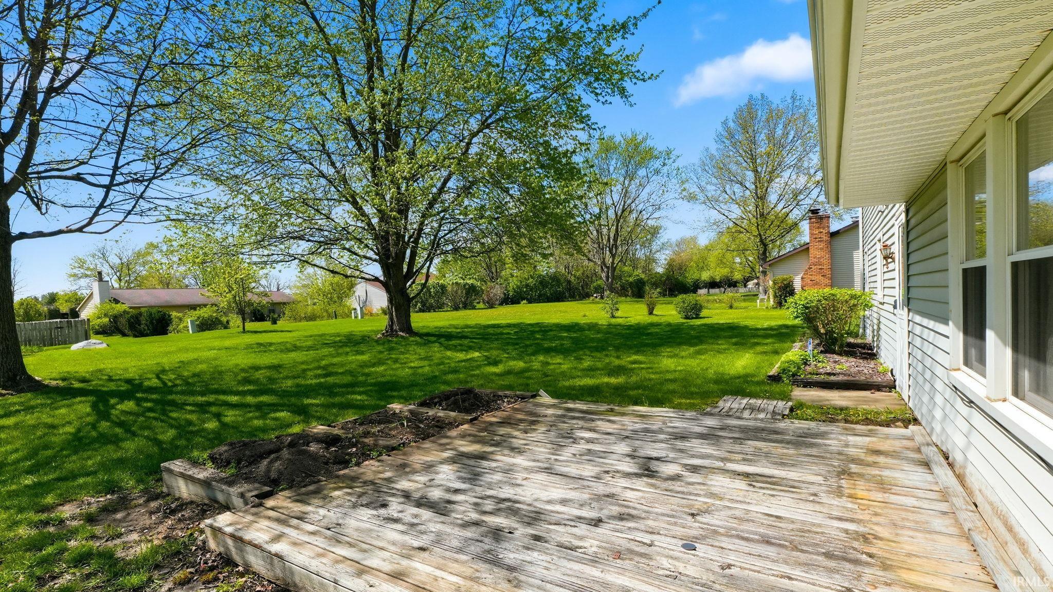 Expansive outdoor deck with natural wood planks, offering access to a substantial green lawn