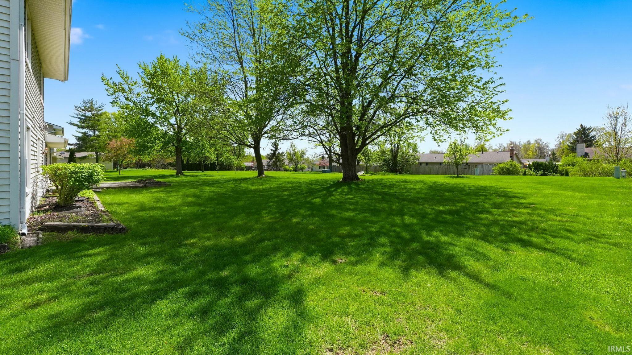 Expansive green lawn with mature trees providing natural shading