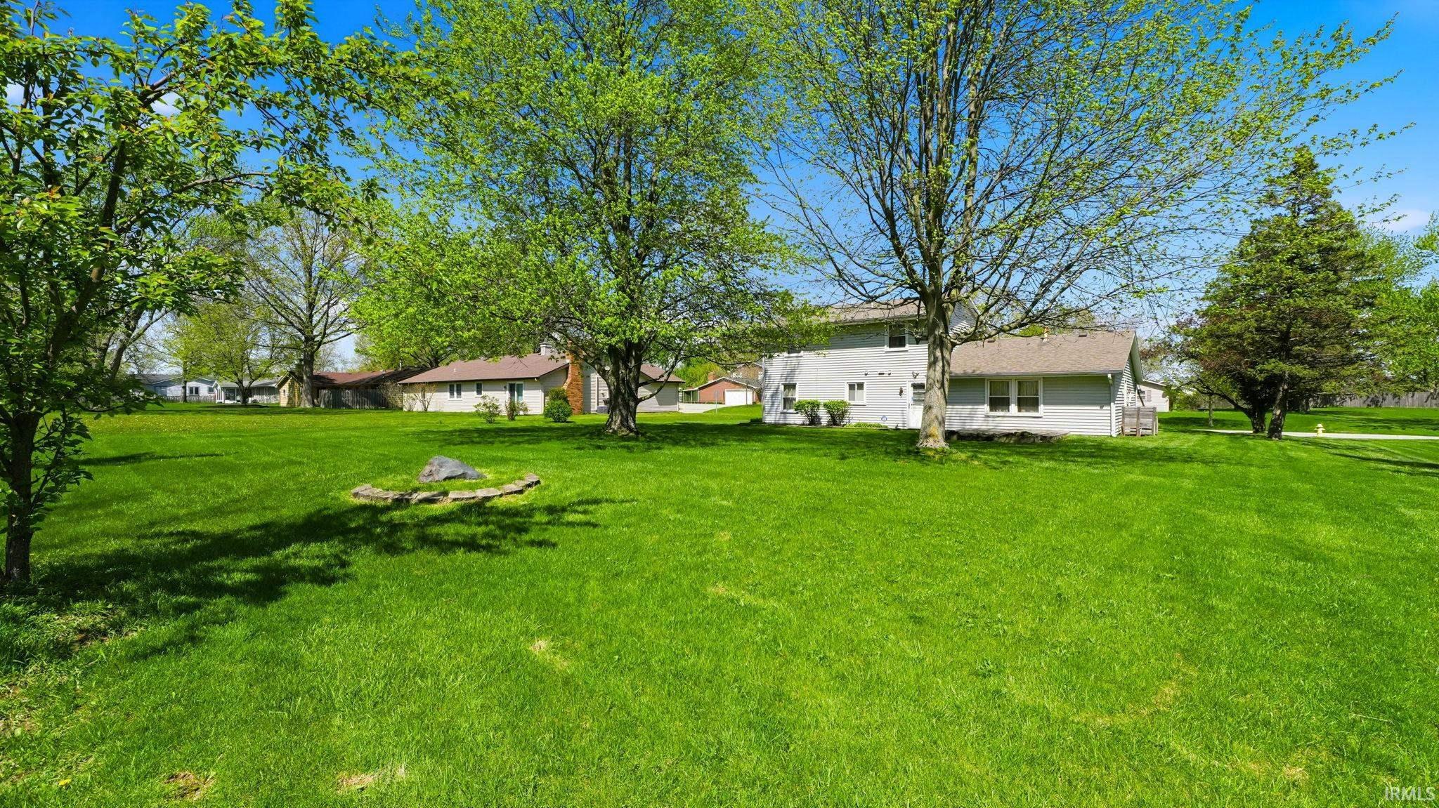 Expansive green lawn with mature trees and a rock feature
