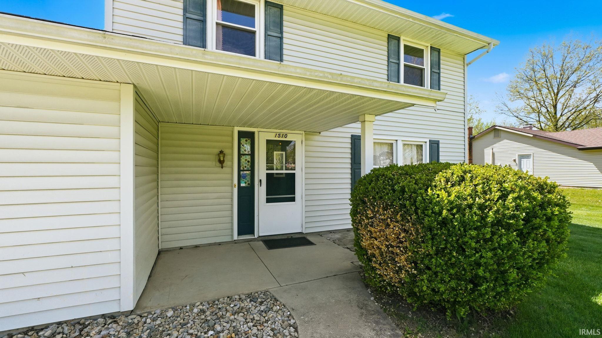Entryway featuring a white storm door, dark green main door, and a built-in light fixture