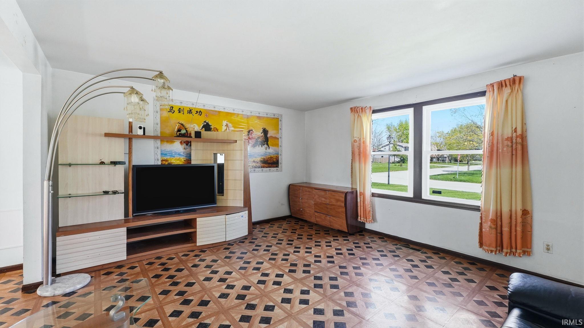 Spacious interior featuring patterned wood-finish flooring, white walls, and a large multi-pane window