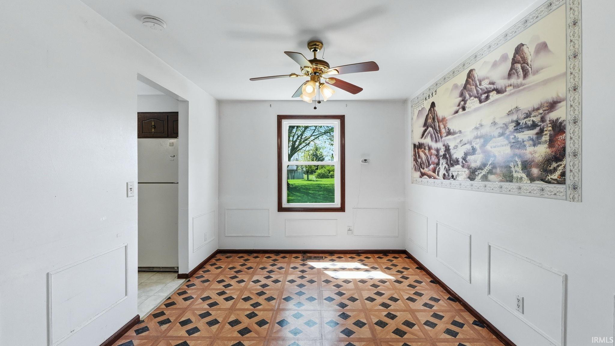 Room featuring patterned flooring, wainscoting, and a ceiling fan with integrated lighting