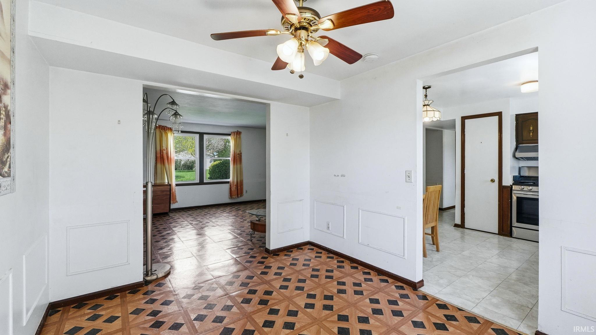 Hardwood-style flooring with a geometric pattern, ceiling fan with integrated lighting, and white trim molding