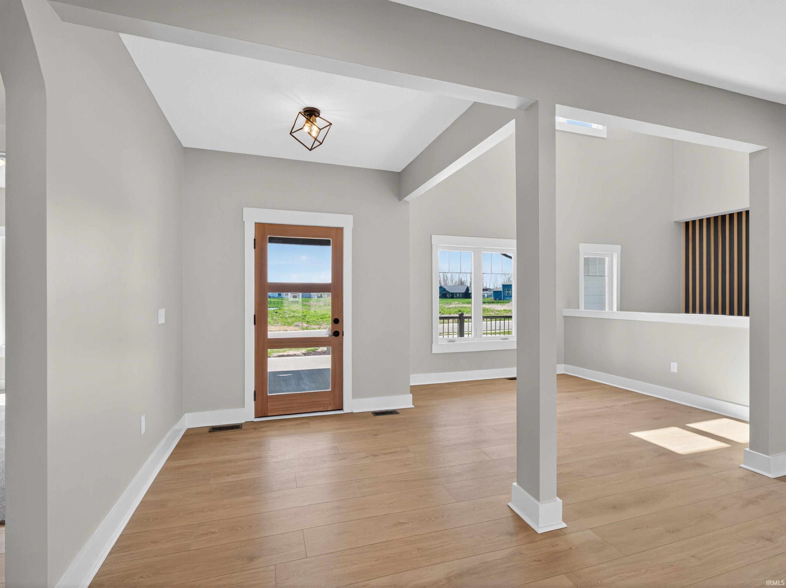 Entryway featuring a wood-finish door with multiple glass lites, wood-finish flooring, and a modern geometric flush-mount light fixture