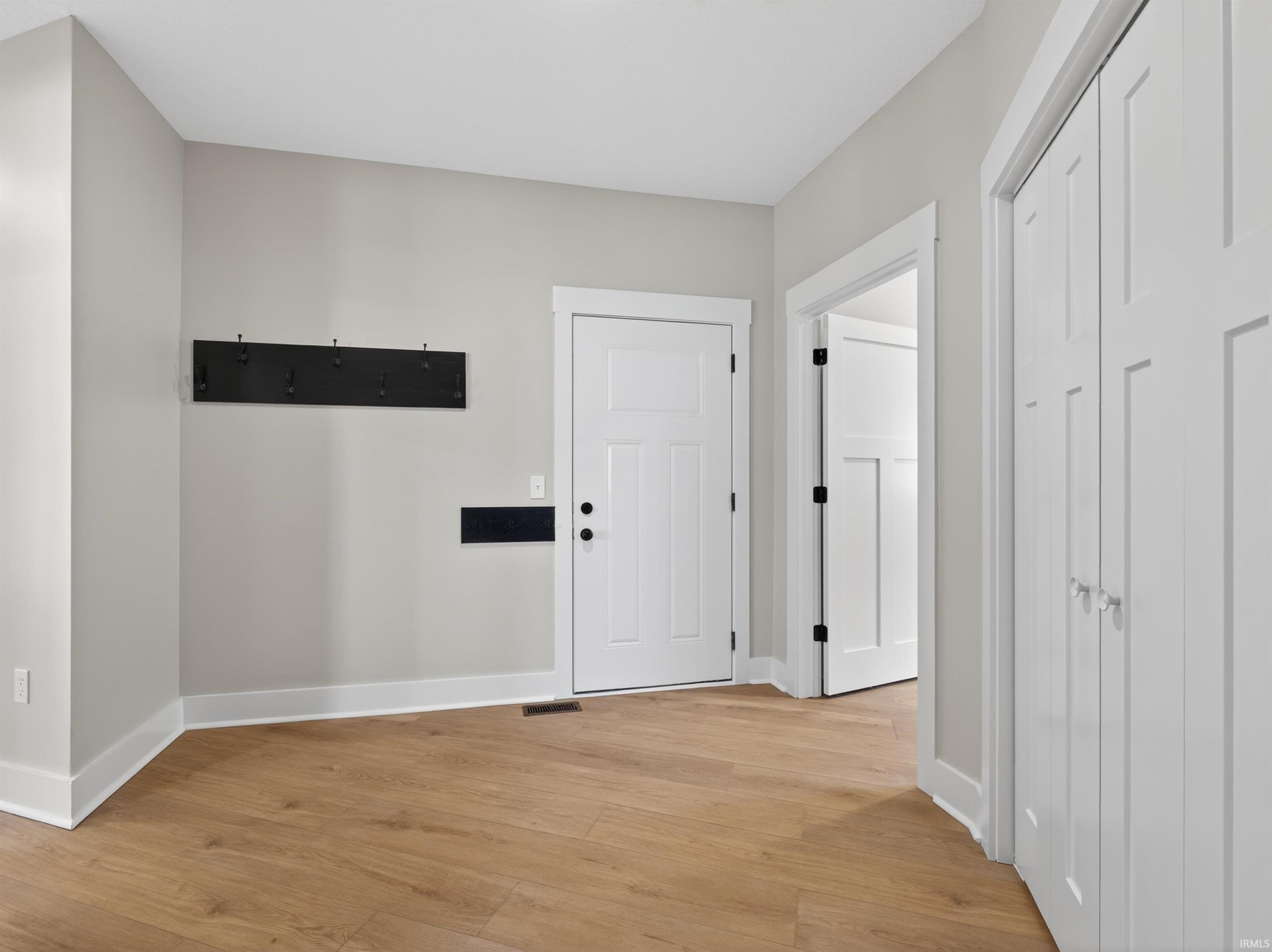 Foyer featuring wood-finish flooring, light gray wall paint, and white trim