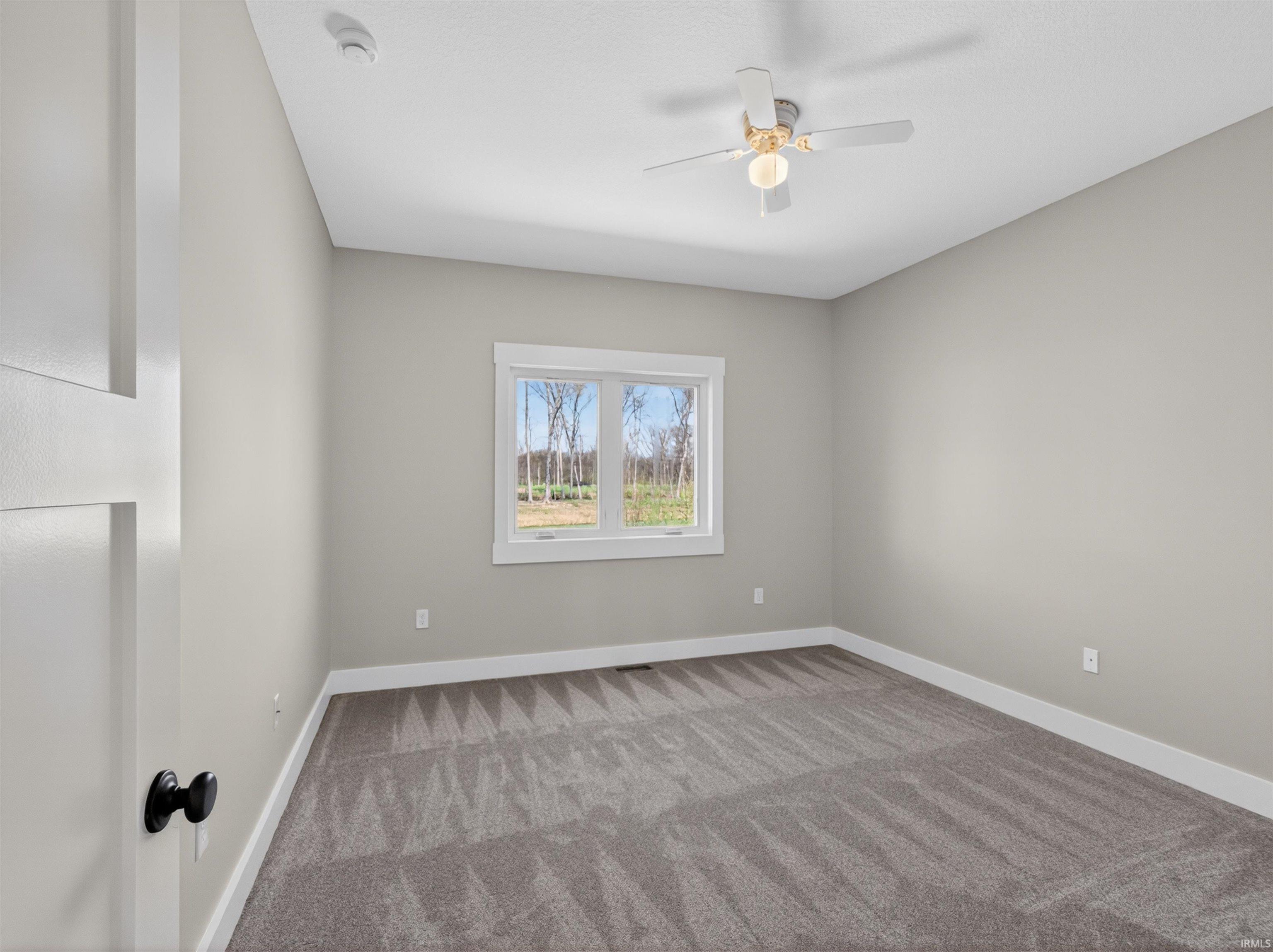 Room featuring a single window, overhead ceiling fan with lighting, light gray wall paint, white trim, and gray patterned carpeting