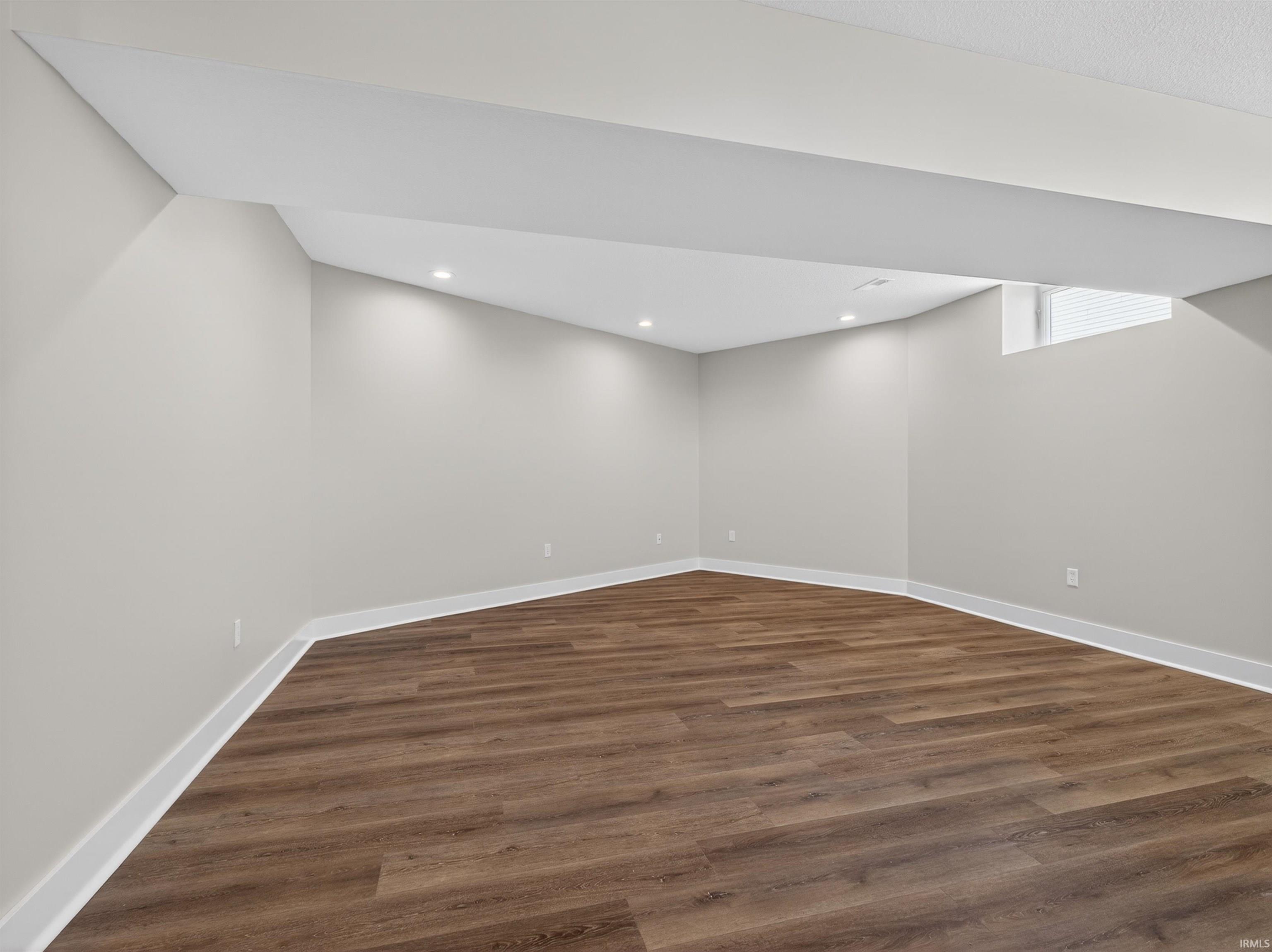 Spacious room featuring wood-finish flooring, light gray walls, white trim, and recessed lighting