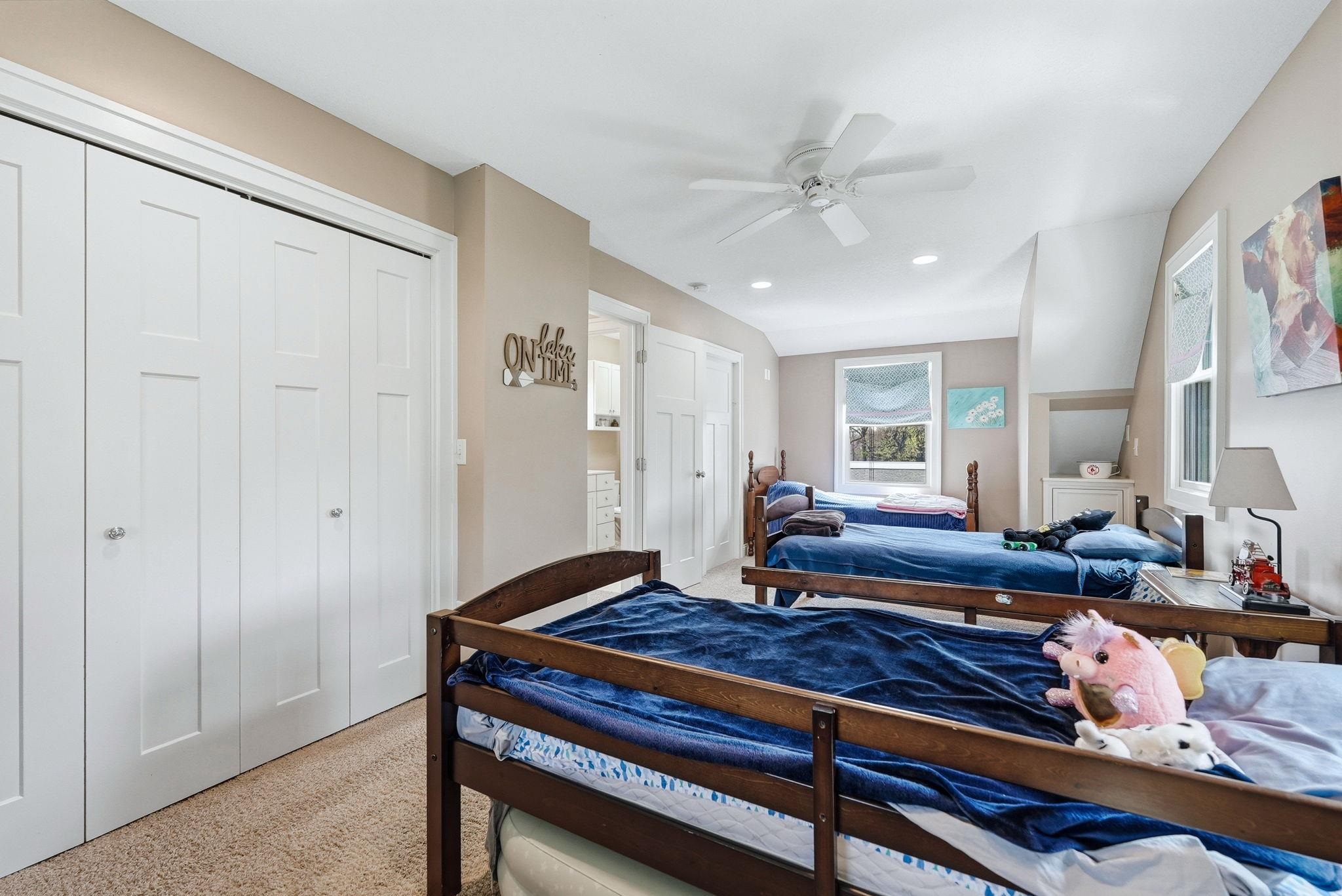 Carpeted room featuring multiple windows, a ceiling fan with integrated lighting, and white bi-fold closet doors