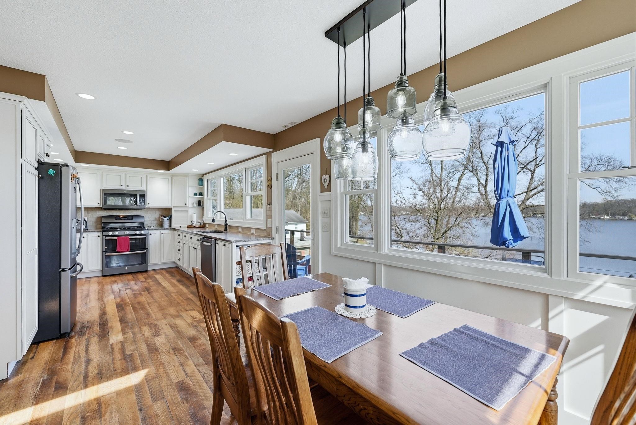 Open-concept dining area with wood-finish flooring and a multi-light pendant fixture