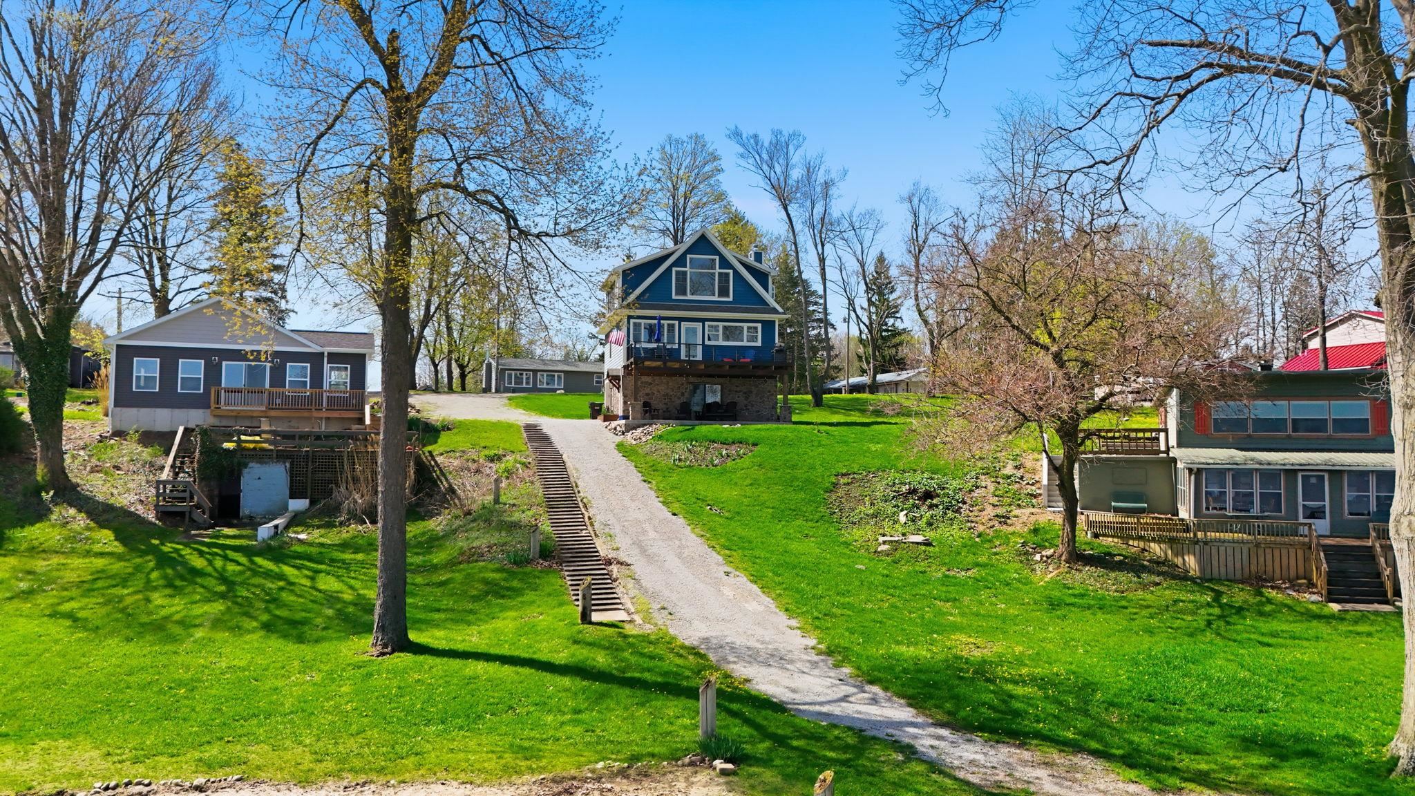 Multiple properties featuring elevated rear decks and sloped, grassed landscaping