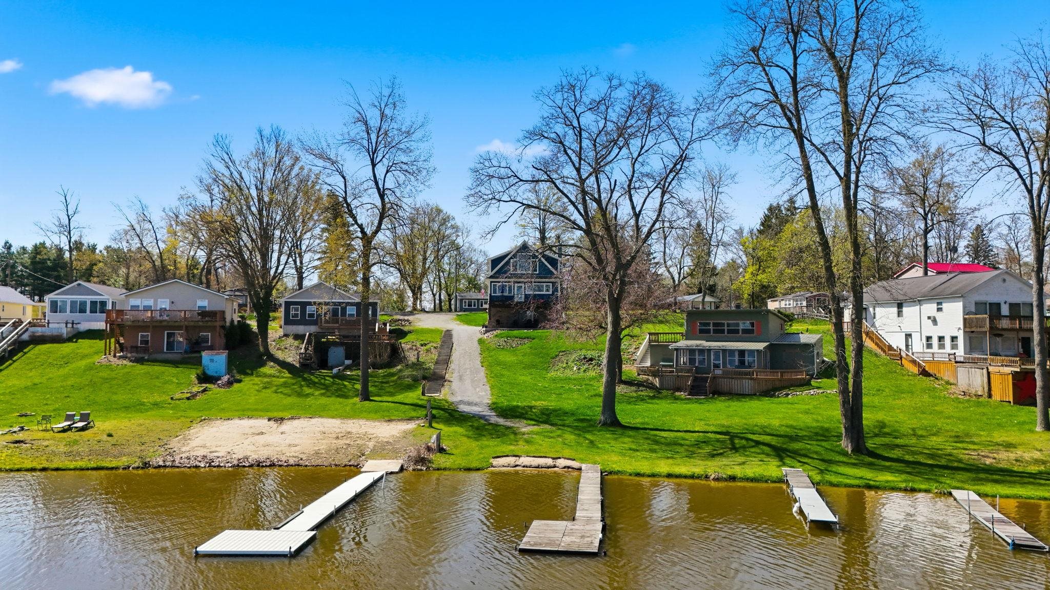 Waterfront property featuring a private boat dock, sandy shore, and expansive grassy yard