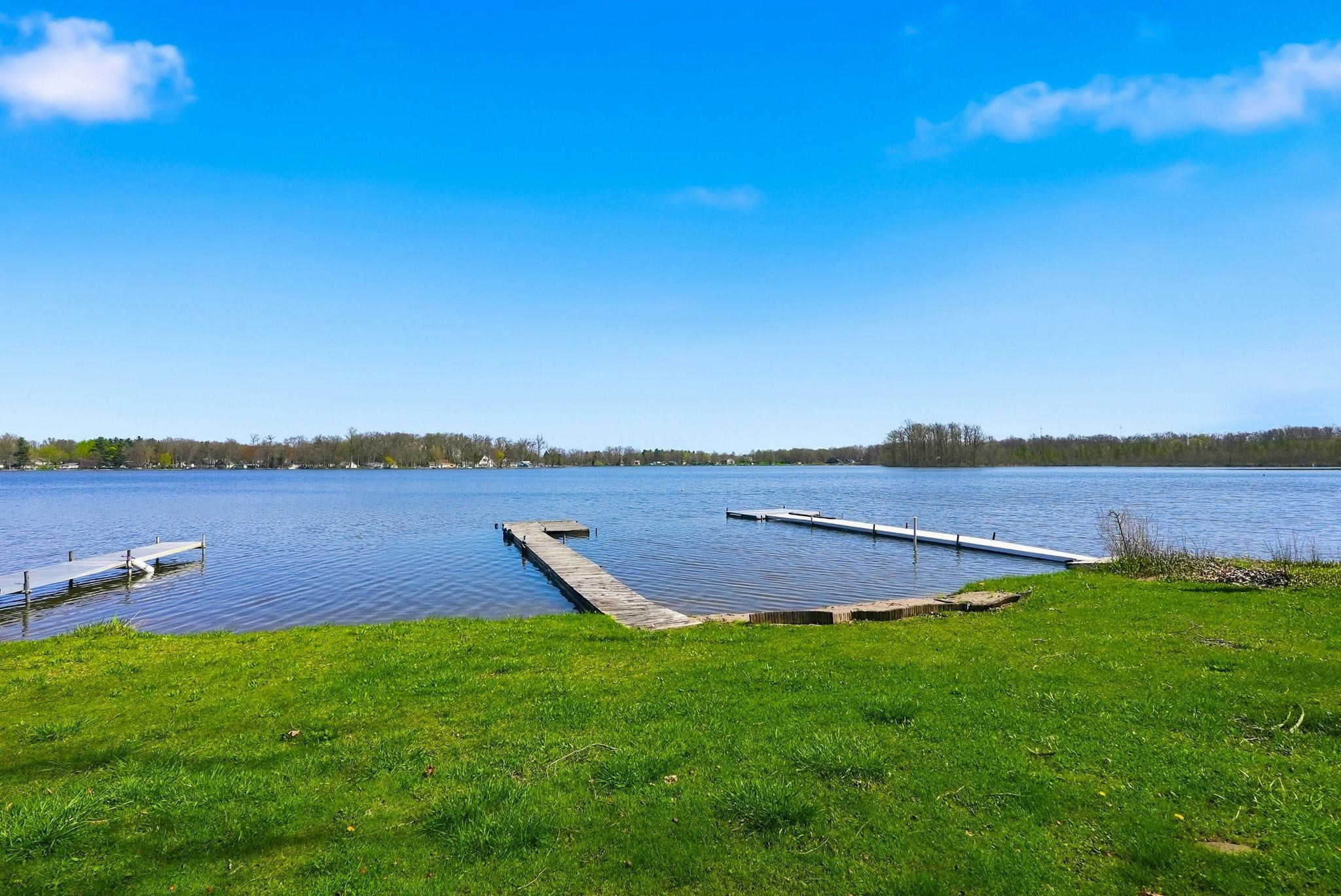 Lakefront property featuring a grassy shoreline, two private docks, and expansive water frontage