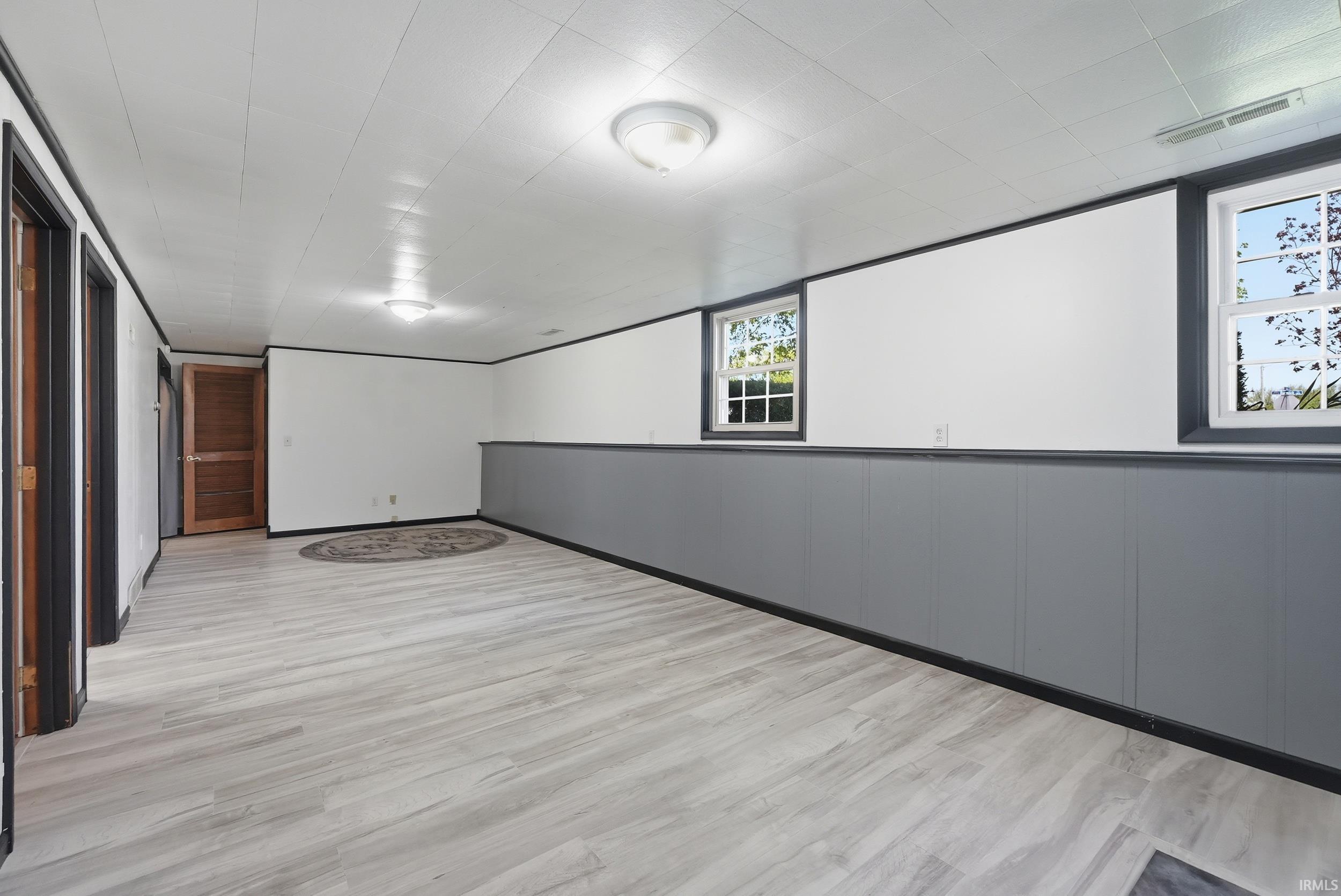 Spacious room featuring light wood-finish flooring, white paneling on the ceiling, and recessed lighting