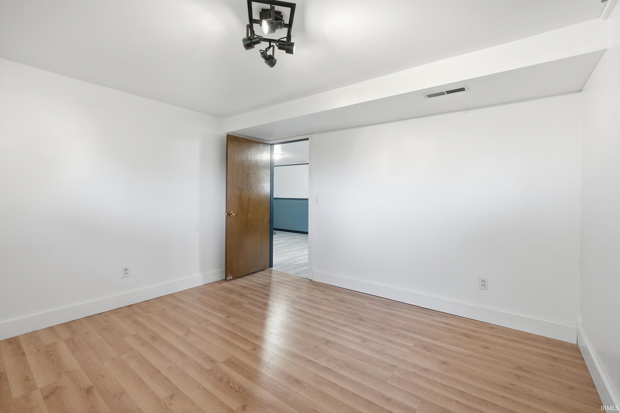 Room featuring light wood-finish flooring, white painted walls, and white baseboards